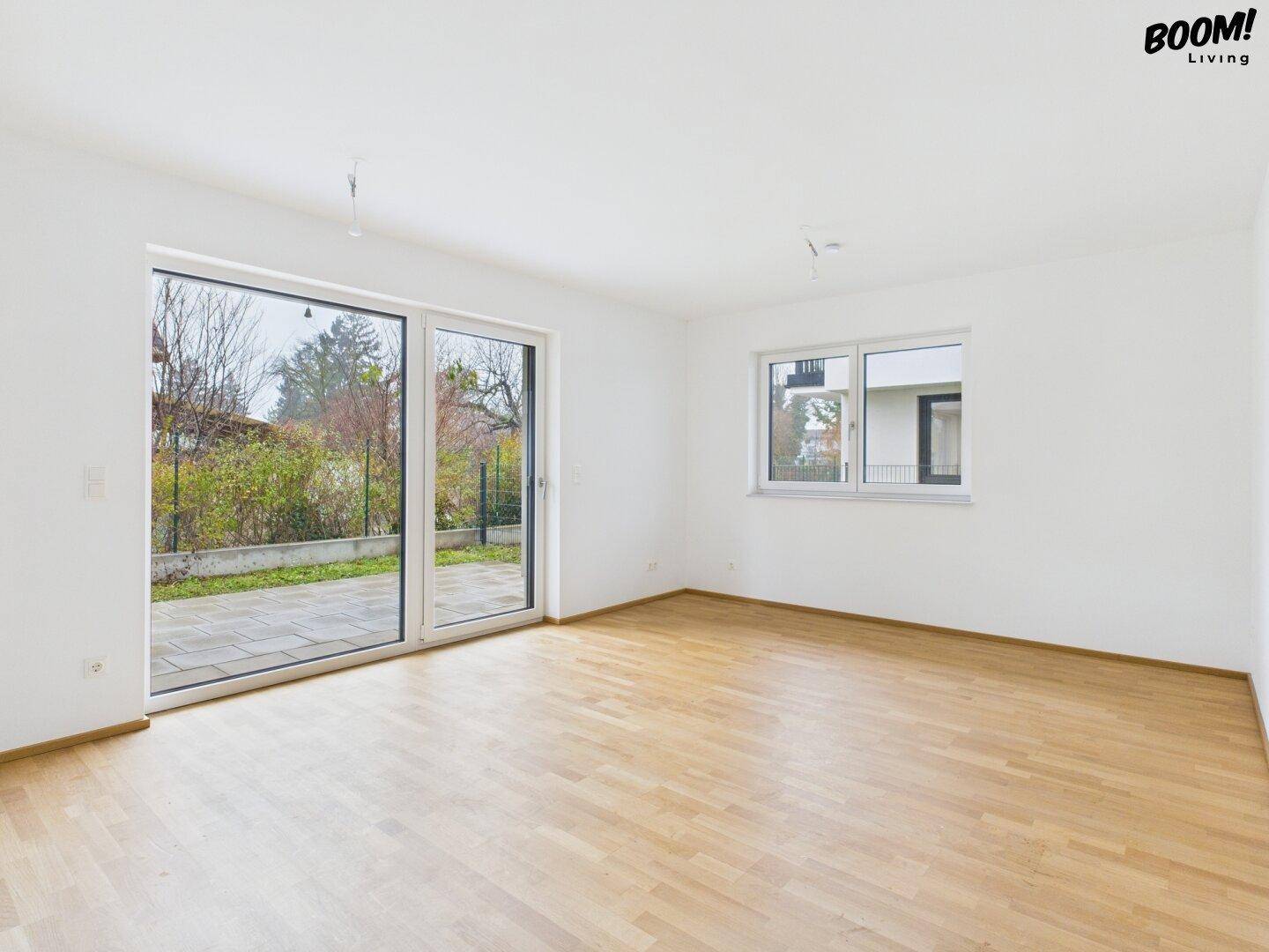 Geräumiger, heller Wohnbereich mit Holzboden und großen Schiebetüren zur Terrasse.
