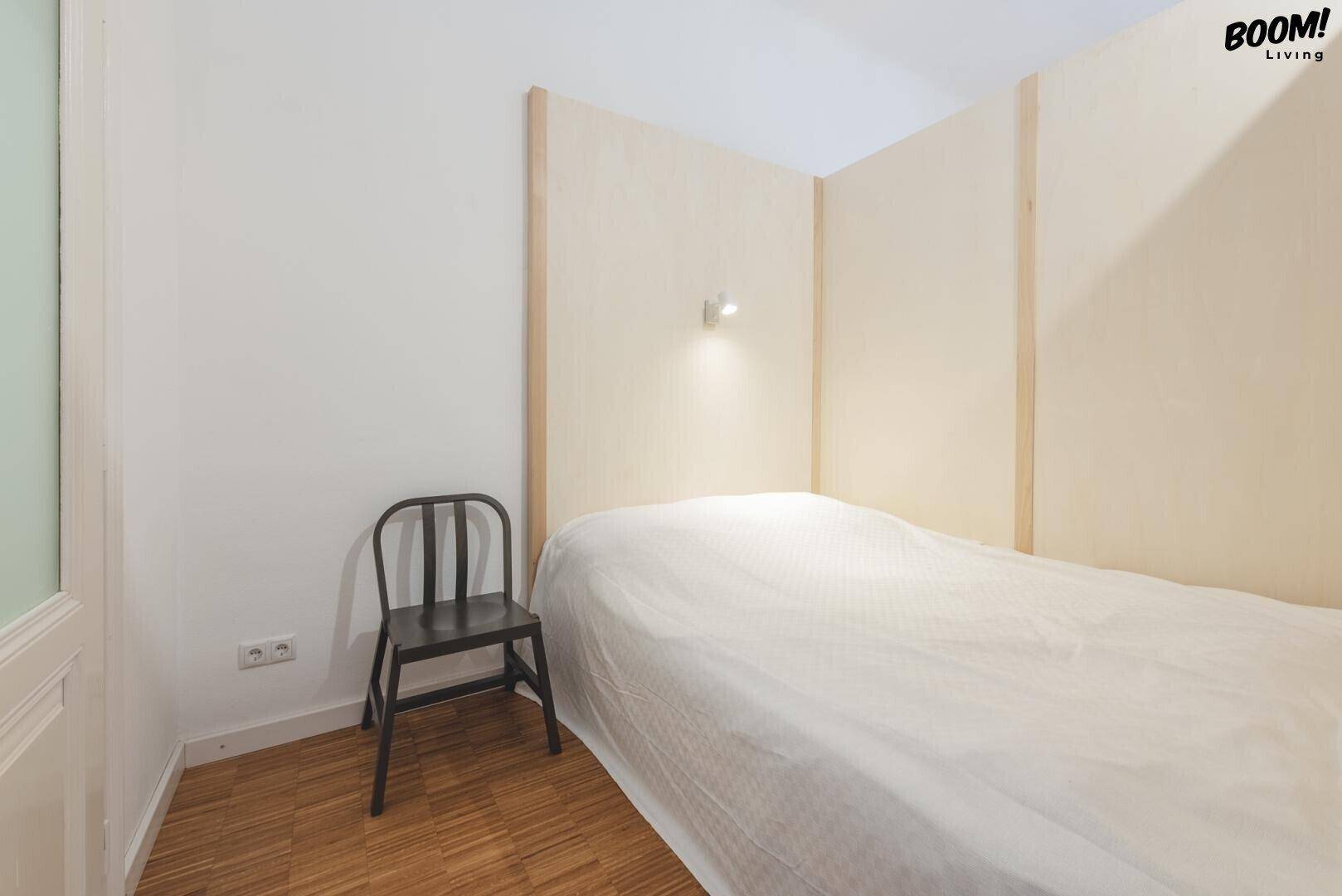 Kleiner, abgetrennter Schlafbereich mit einem Bett und minimalistischer Einrichtung, ideal für Einzelpersonen.