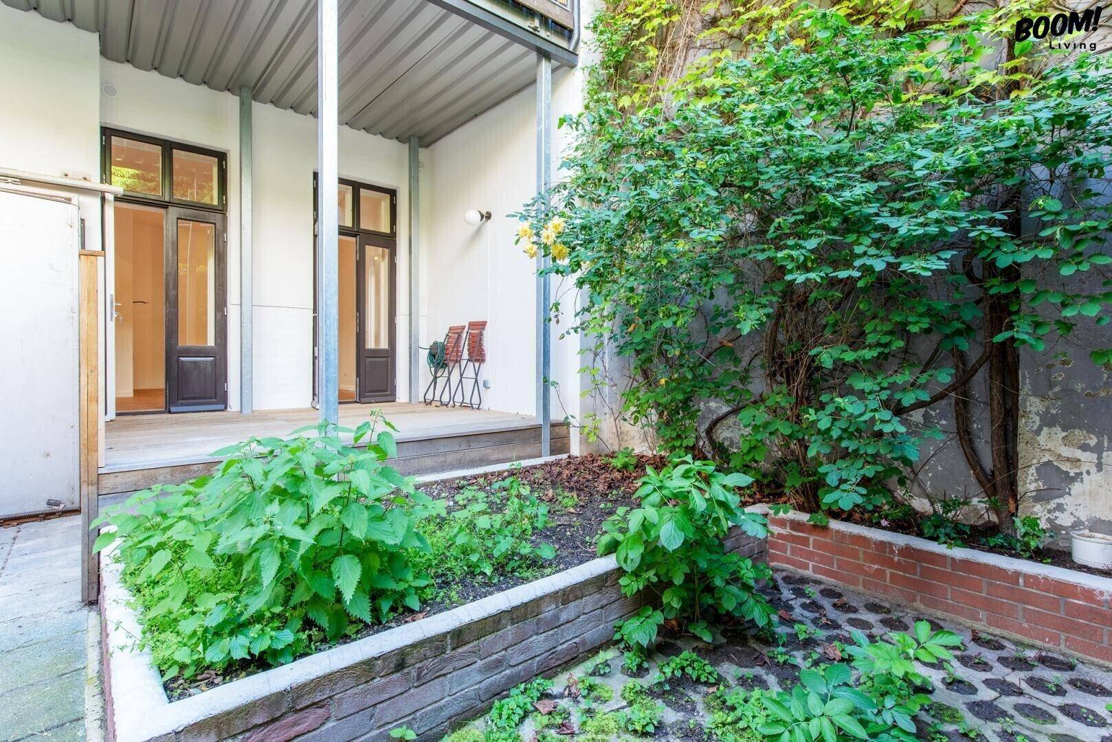 Kleiner Gartenbereich mit Hochbeeten und verschiedenen Pflanzen, direkt zugänglich vom Gebäude.