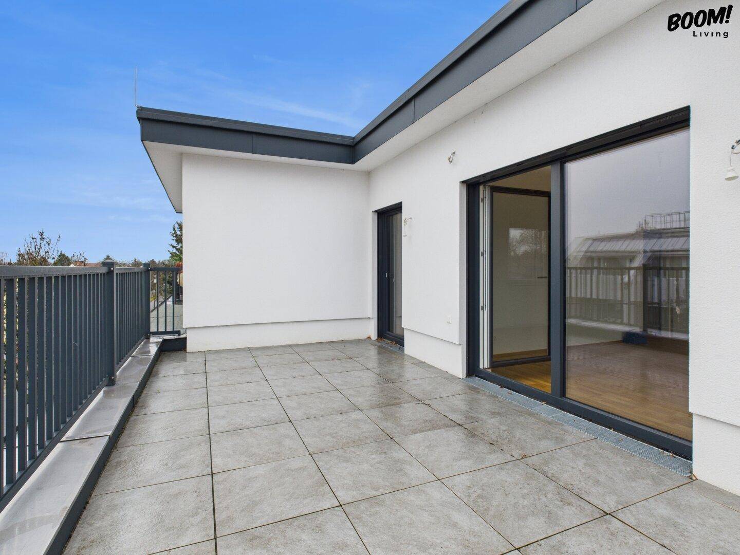 Große, geflieste Terrasse mit moderner Brüstung und viel Platz für Outdoor-Möbel.
