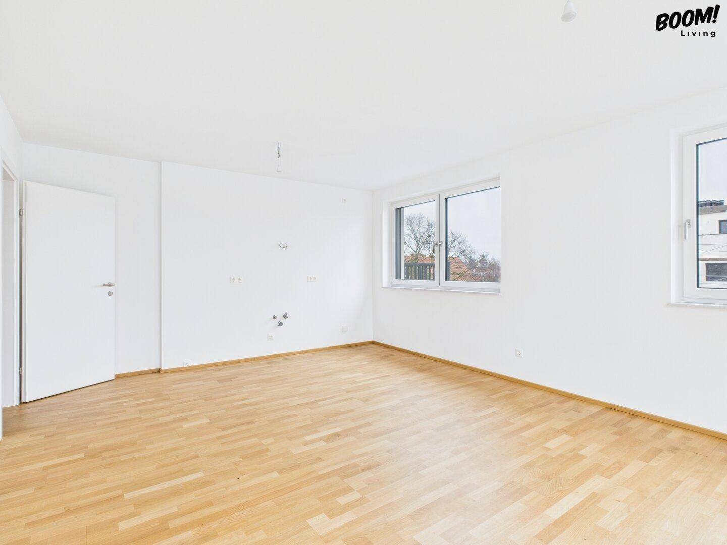 Unmöbliertes Zimmer mit Holzboden und mehreren Fenstern, bietet viel Tageslicht.
