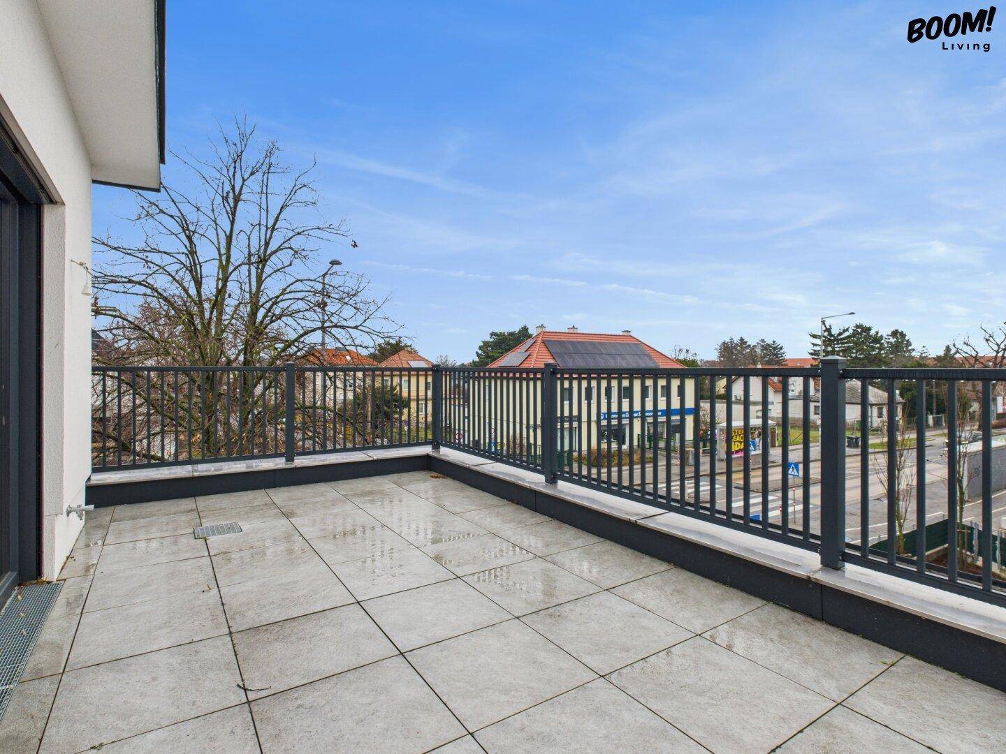Geräumiger Balkon mit Fliesenboden und Blick auf die Umgebung und die Straße.