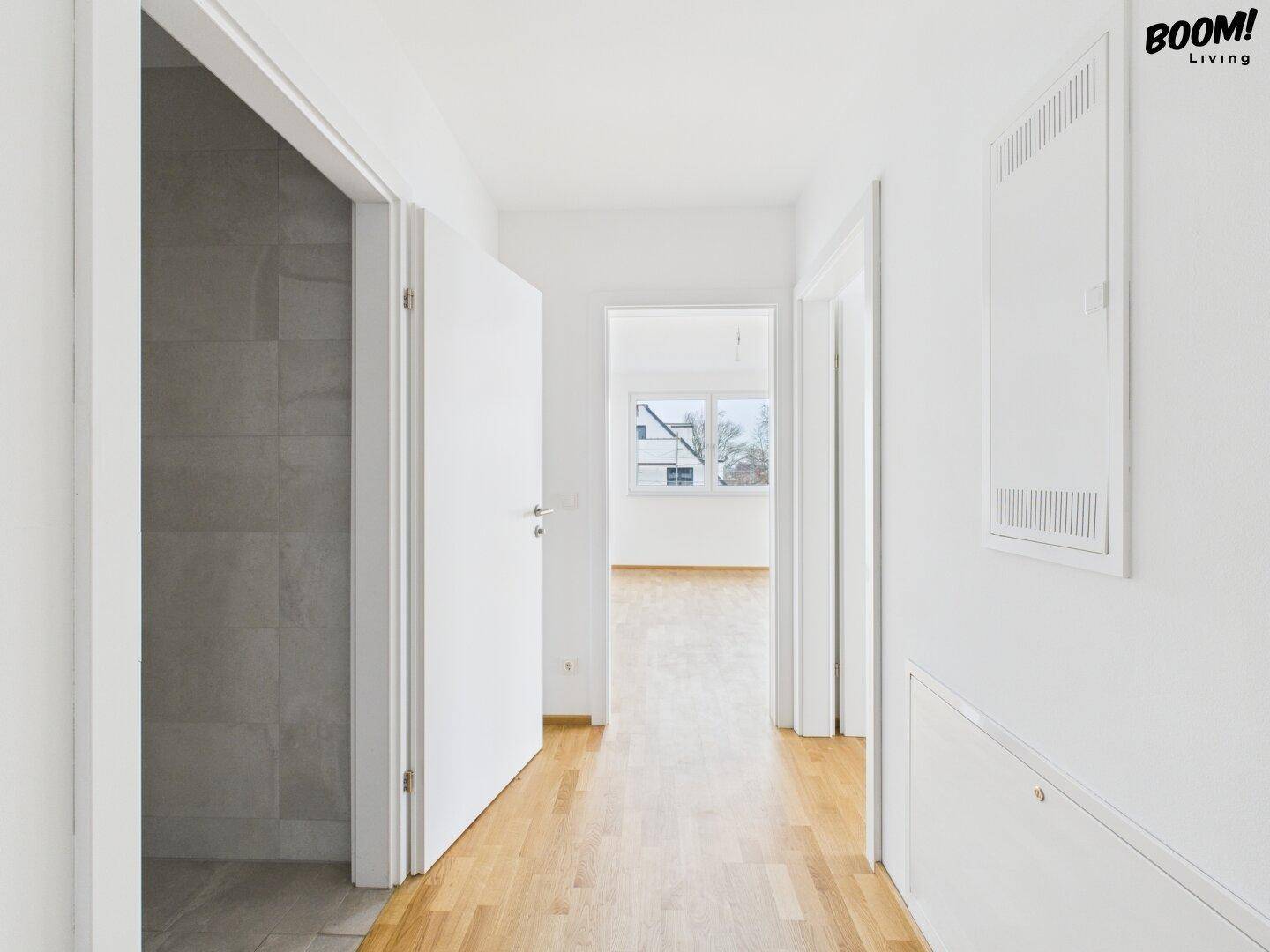 Heller Flur mit Holzboden, der zu verschiedenen Zimmern und einem Badezimmer führt.
