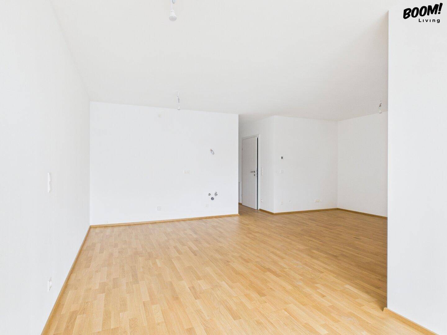 Leerer Raum mit hellem Parkettboden und weißen Wänden, bereit zur individuellen Gestaltung.