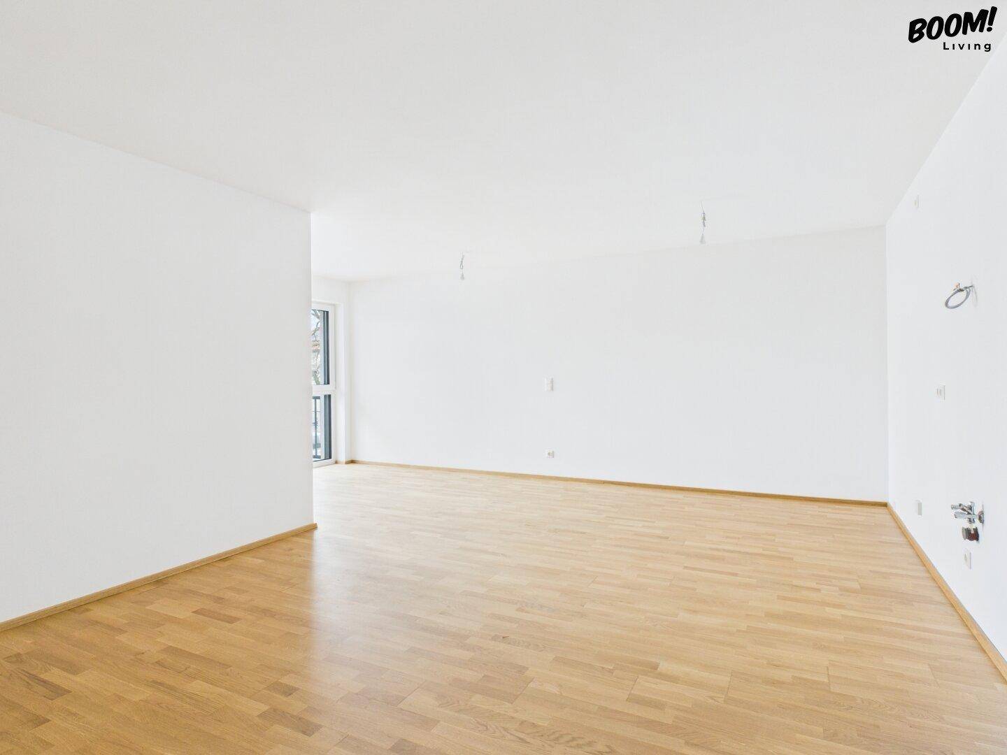 Heller, leerer Raum mit Parkettboden und weißen Wänden, ideal für verschiedene Nutzungen.