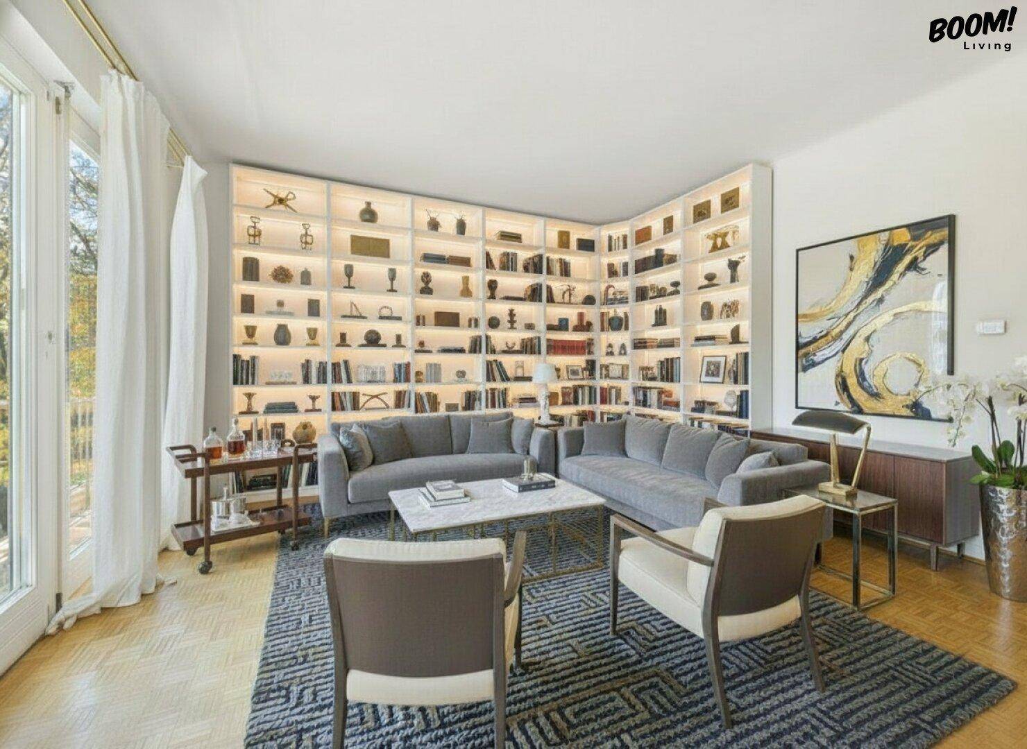 Elegant eingerichtetes Wohnzimmer mit Parkettboden, bequemen Sofas und beleuchteter Bücherwand.
