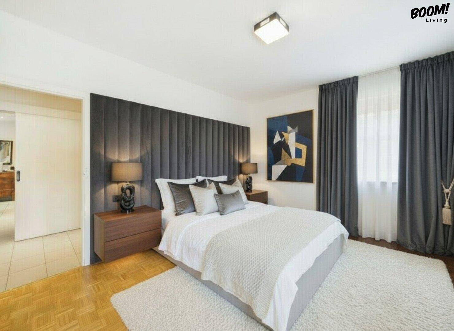 Modernes Schlafzimmer mit großem Bett, gepolstertem Kopfteil und eleganten dunklen Vorhängen.