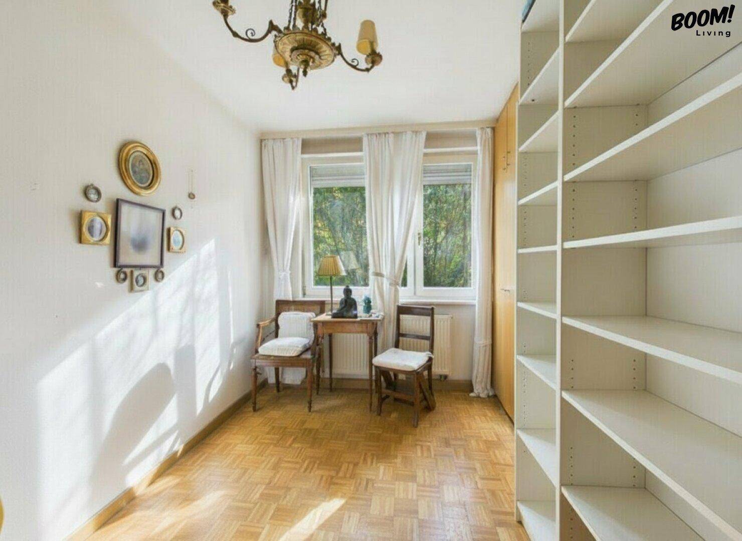 Kleiner, heller Raum mit Parkettboden, Fenstern und einem leeren Bücherregal, ideal als Büro.