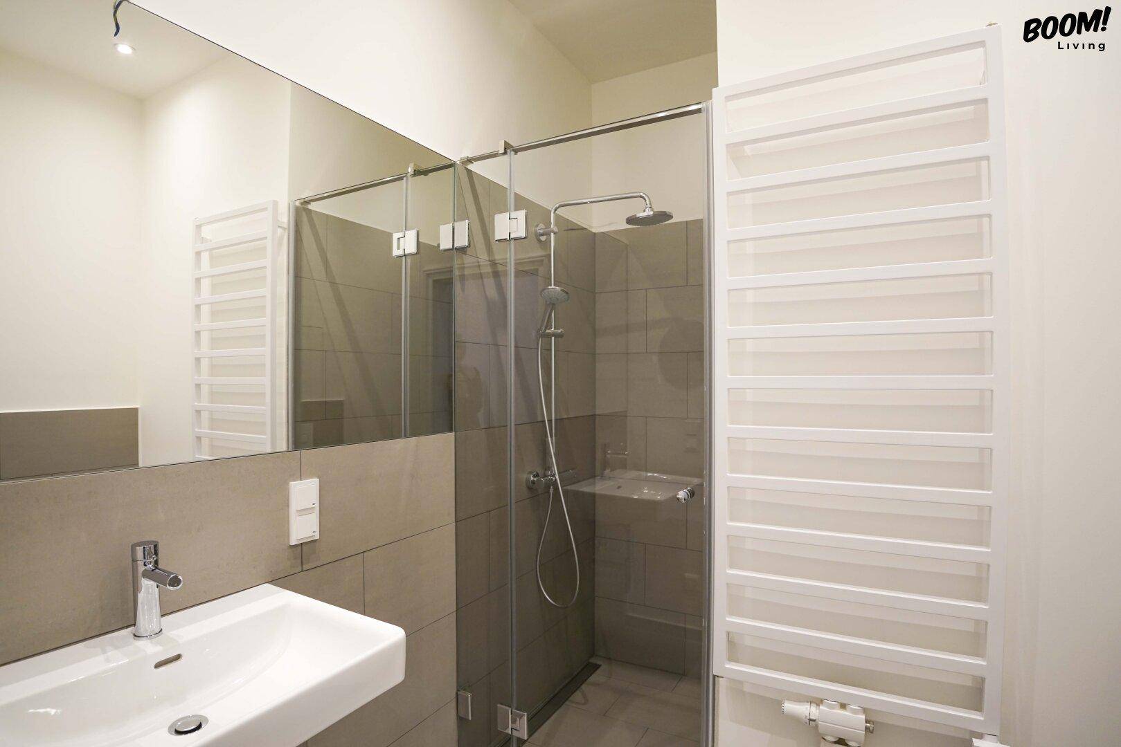 Modernes Badezimmer mit ebenerdiger Dusche, Einzelwaschbecken und beheiztem Handtuchhalter.