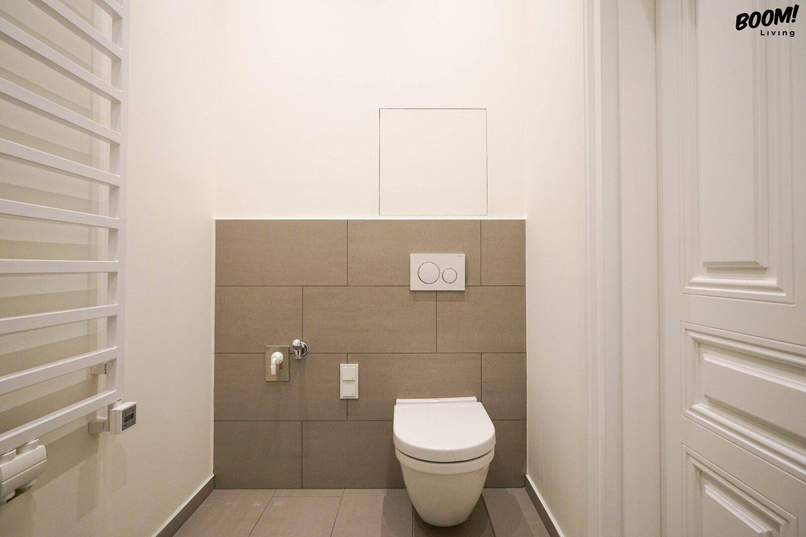 Separates WC mit wandhängender Toilette und modernem Fliesenbereich.