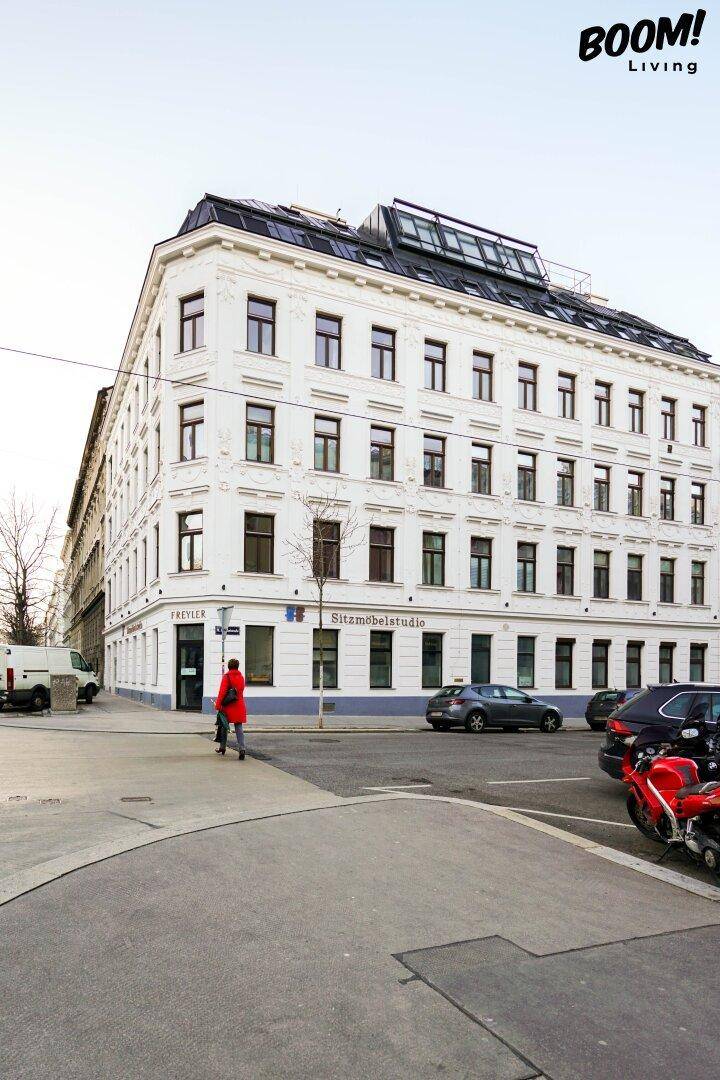 Historisches Eckgebäude mit modernem Dachausbau und Geschäften im Erdgeschoss.