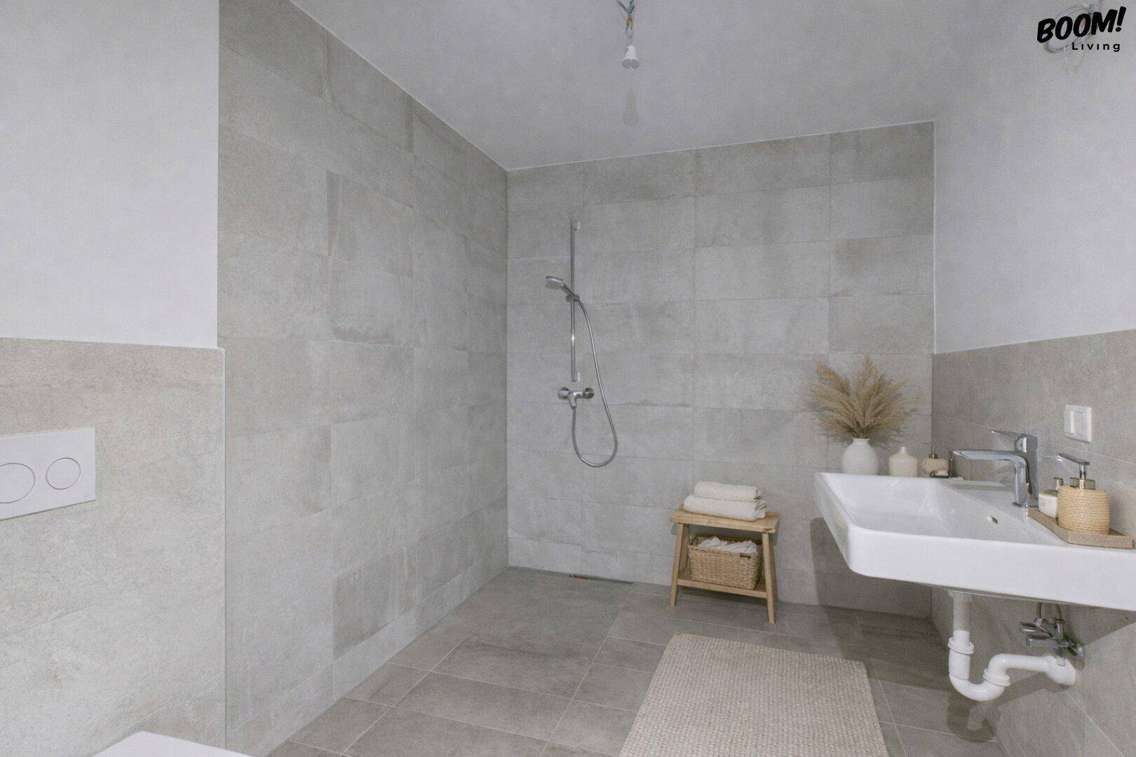 Modernes Badezimmer mit ebenerdiger Dusche, hellen Fliesen und Einzelwaschbecken.