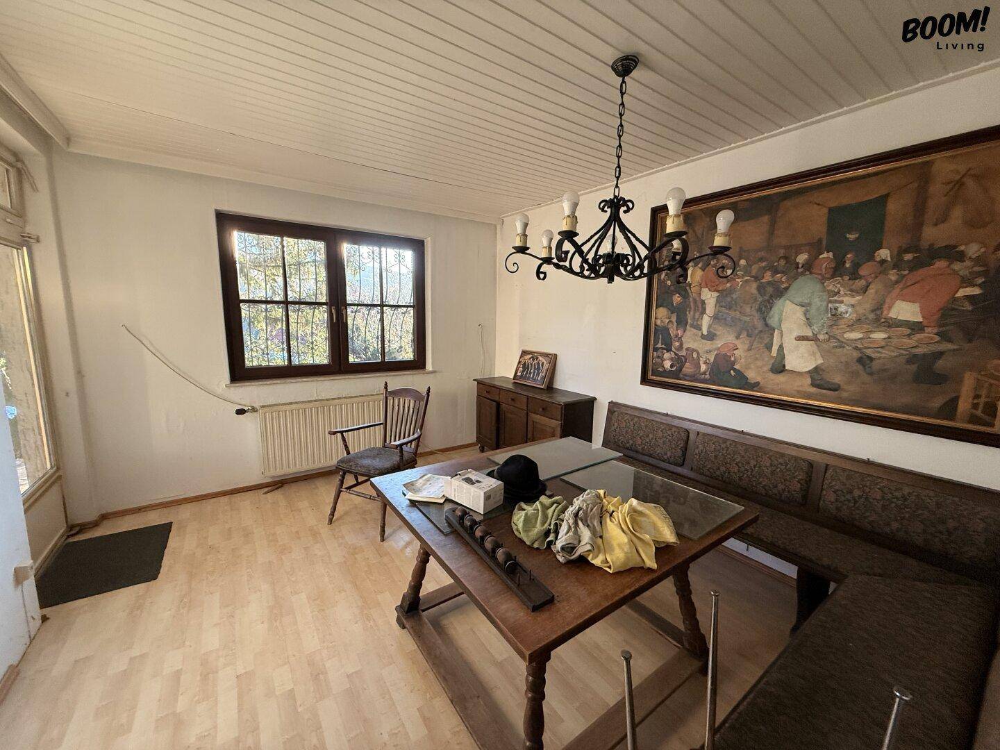 Esszimmer mit traditionellem Holztisch, Sitzbank und großem Wandgemälde.