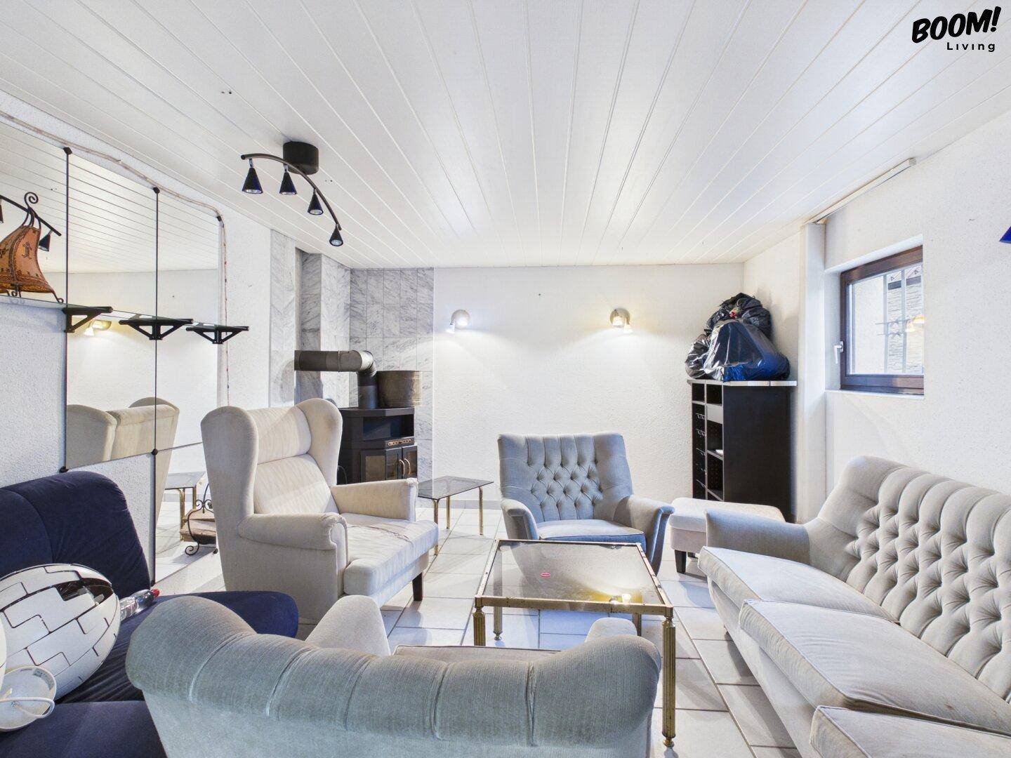 Gemütliches Wohnzimmer im Untergeschoss mit Polstermöbeln und Fliesenboden.