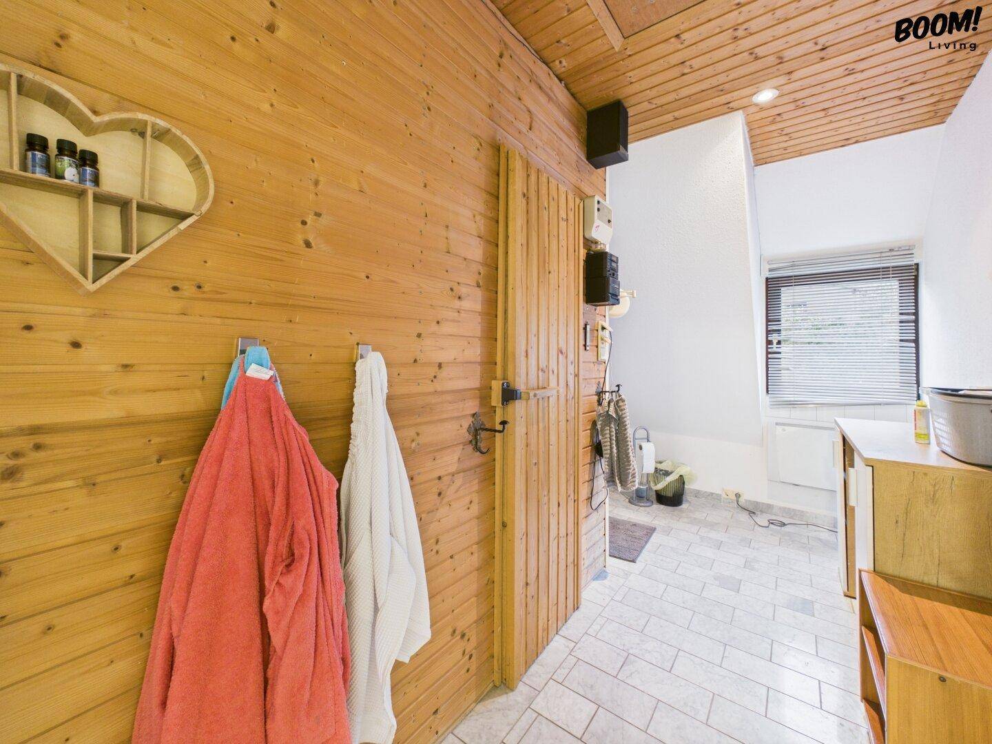 Raum mit rustikaler Holzverkleidung, Fliesenboden und Fenster mit Jalousien.