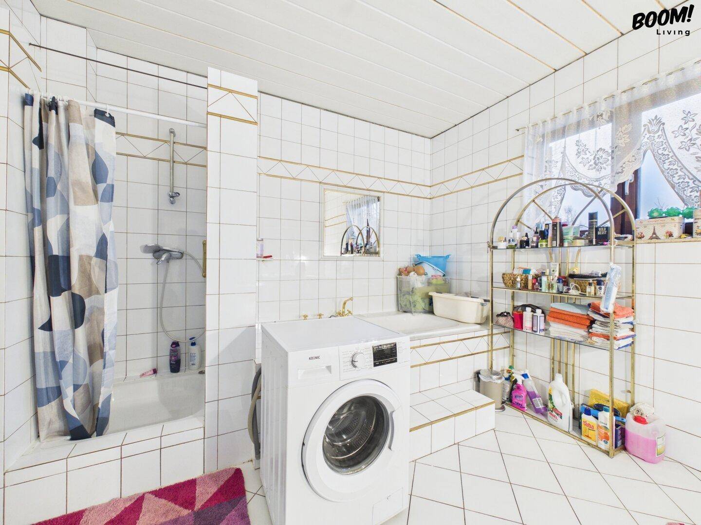 Funktionales Badezimmer mit Duschbereich, Badewanne und Waschmaschine in hellem Design.