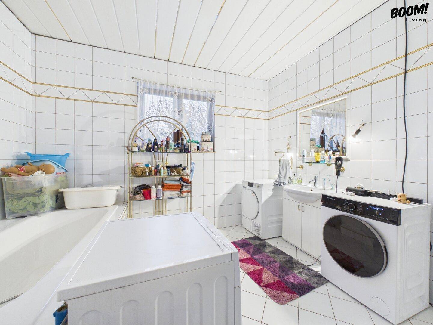 Badezimmer mit Badewanne, Dusche, Waschmaschine und Trockner in klassischem Design.