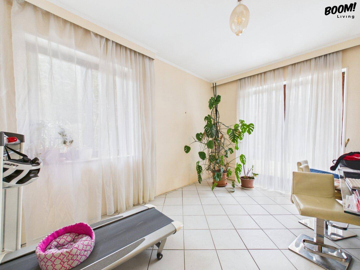 Heller Raum mit Laufband, großen Fenstern und viel Tageslicht, ideal für Sport.