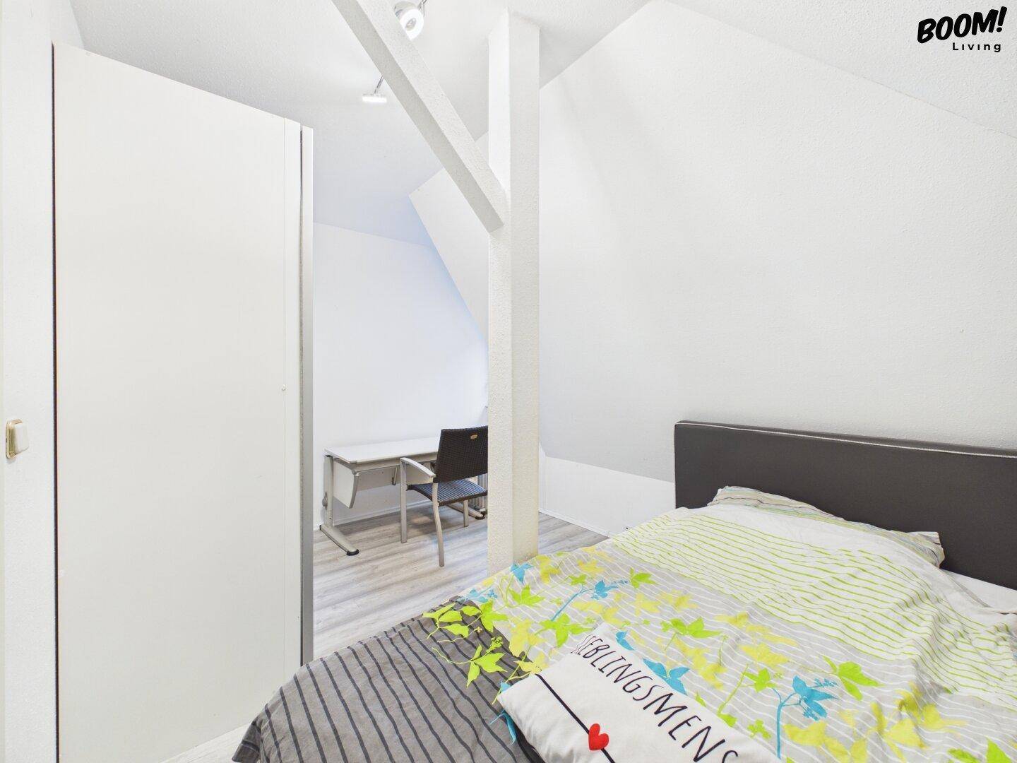 Kleines Schlafzimmer im Dachgeschoss mit Schreibtisch und hellem Laminatboden.