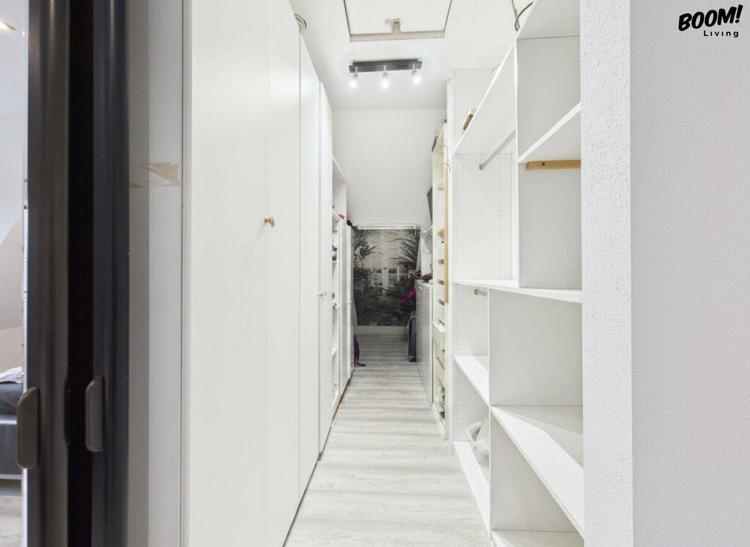 Praktischer begehbarer Kleiderschrank mit viel Stauraum und hellem Laminatboden.