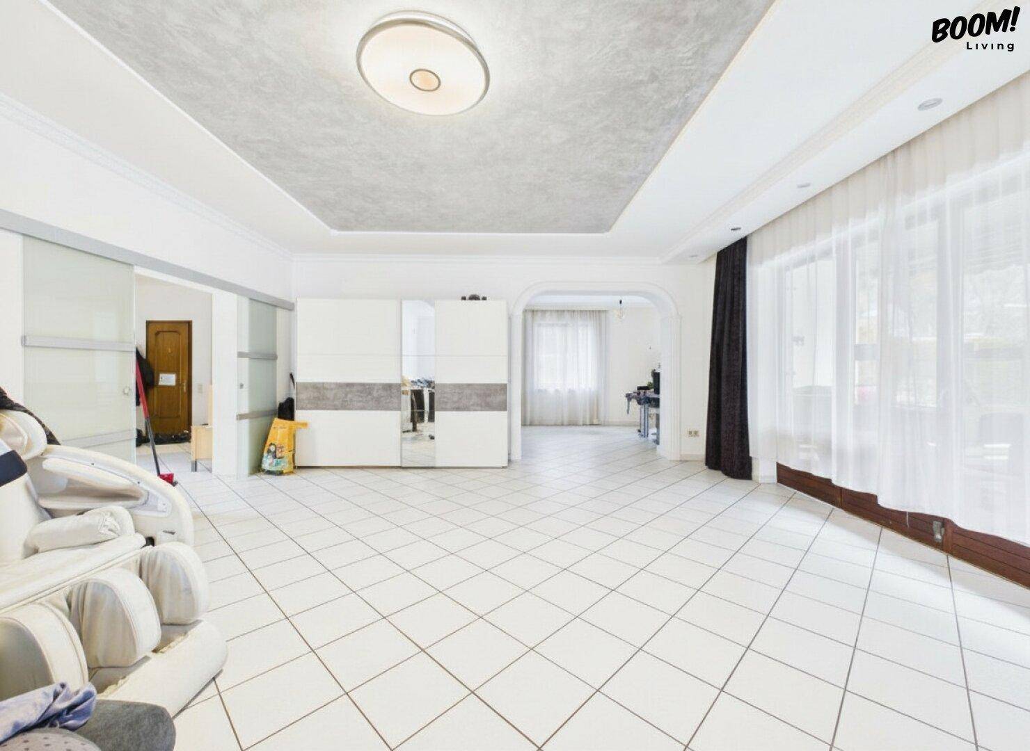 Großzügiger Wohnbereich mit Fliesenboden, viel Tageslicht und Zugang zur Terrasse.