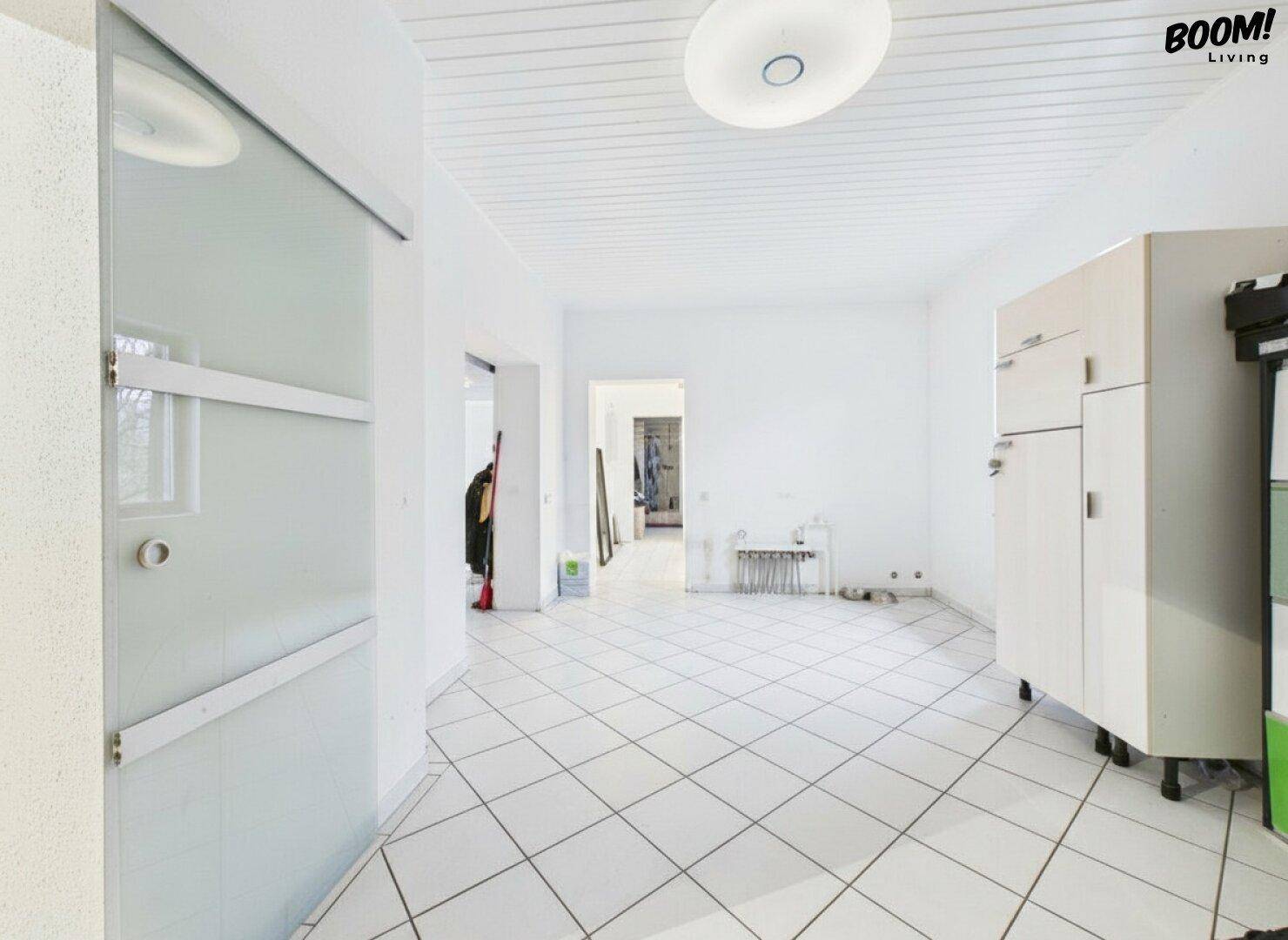 Heller Flur mit Fliesenboden und viel Tageslicht, der verschiedene Räume verbindet.