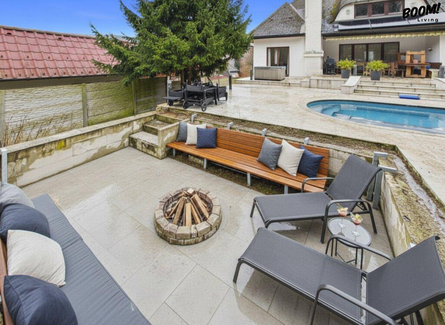 Attraktiver Außenbereich mit Feuerstelle, bequemen Sitzgelegenheiten und Blick auf den Pool.