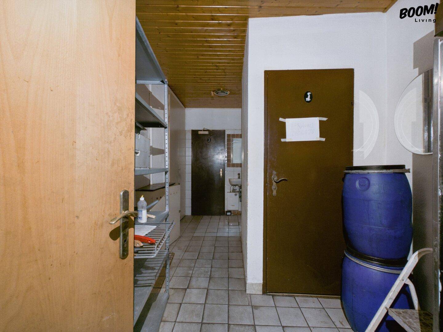Flur in einem Gewerbegebäude mit Fliesenboden, Holzdecke und Lagermöglichkeiten, führt zu weiteren Räumen.