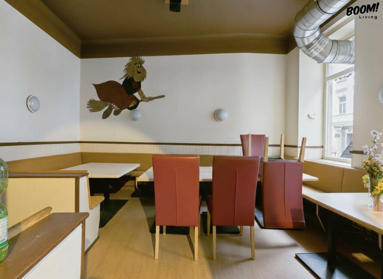 Sitzbereich in einem Café oder Restaurant mit Wandgemälde und bequemen Polsterbänken, helle Atmosphäre.