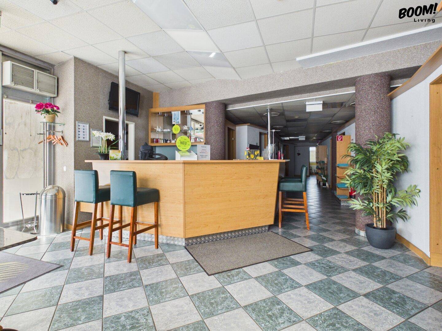 Die Bar mit Holztresen und Barhockern bietet einen einladenden Bereich für Getränke und Gespräche.