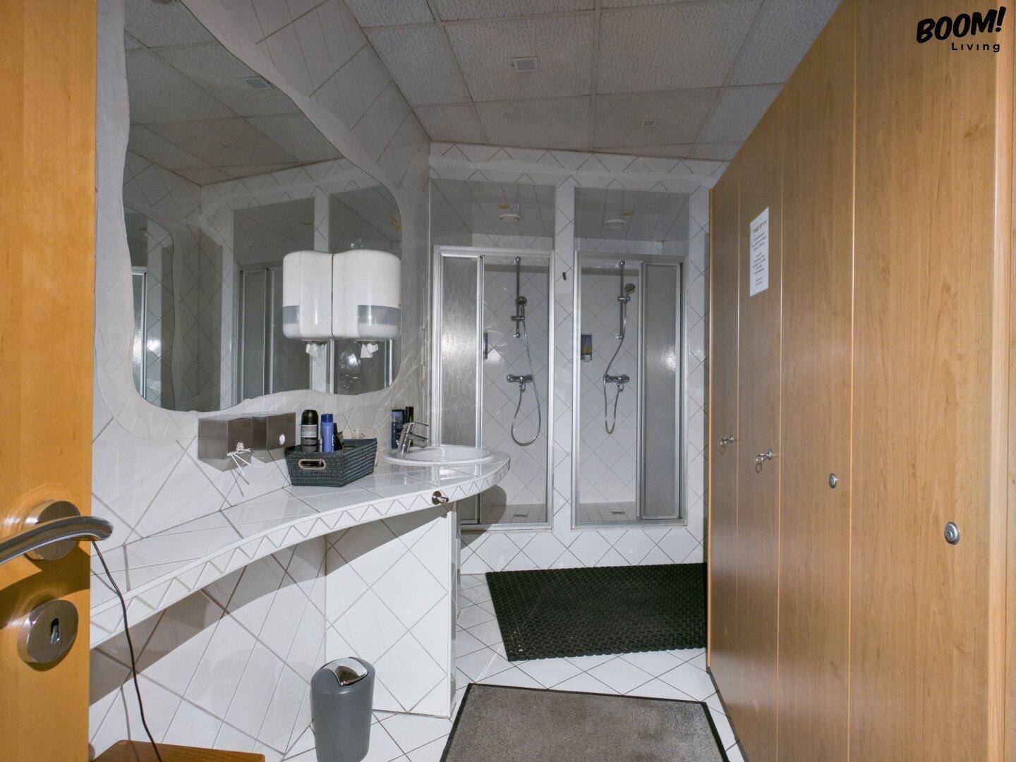 Umkleideraum mit Spinden, Waschbecken und Duschkabinen, alles in funktionalem Design.