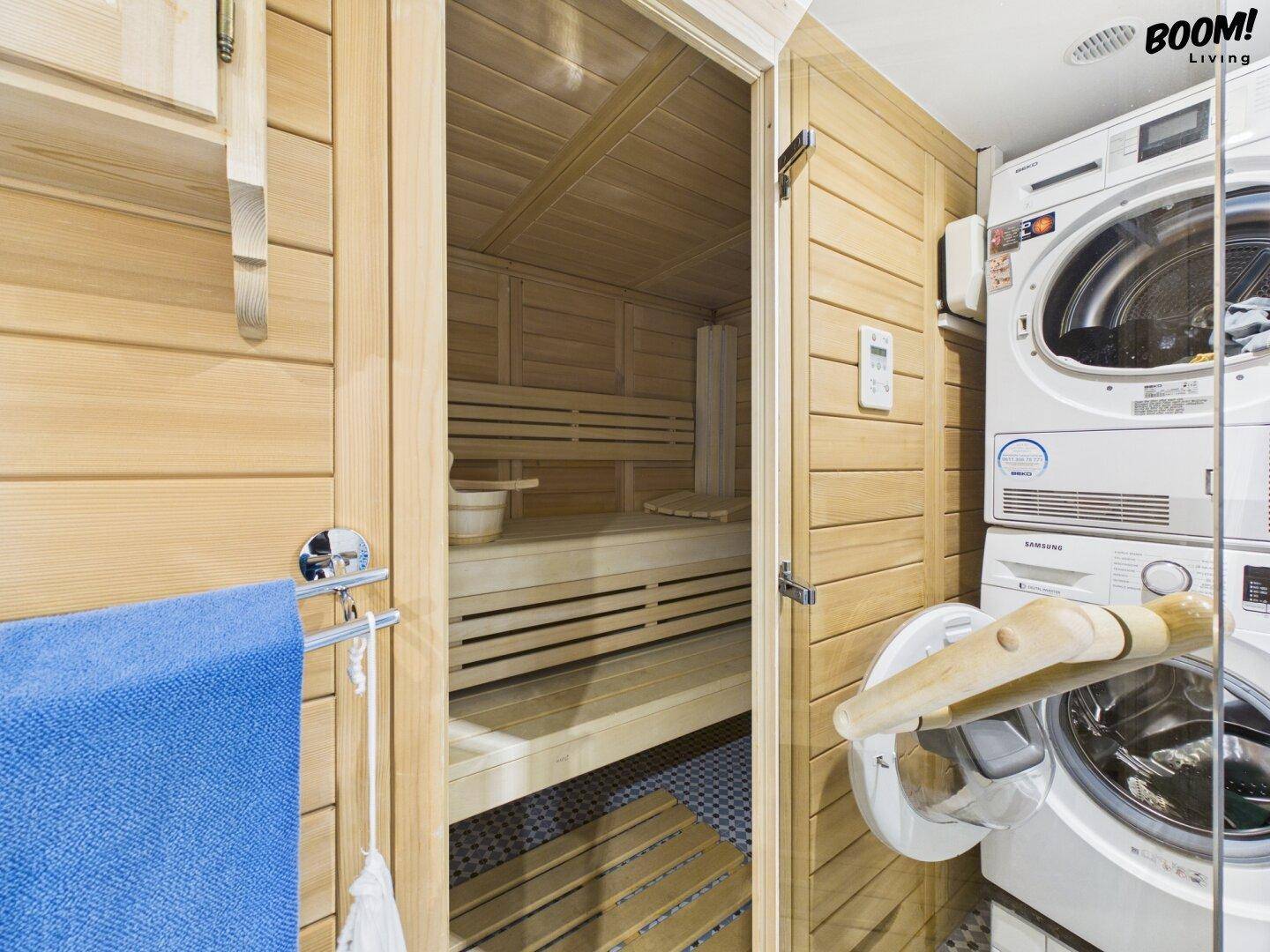 Badezimmer mit integrierter Sauna, Waschmaschine und Trockner für Wellness und Komfort.