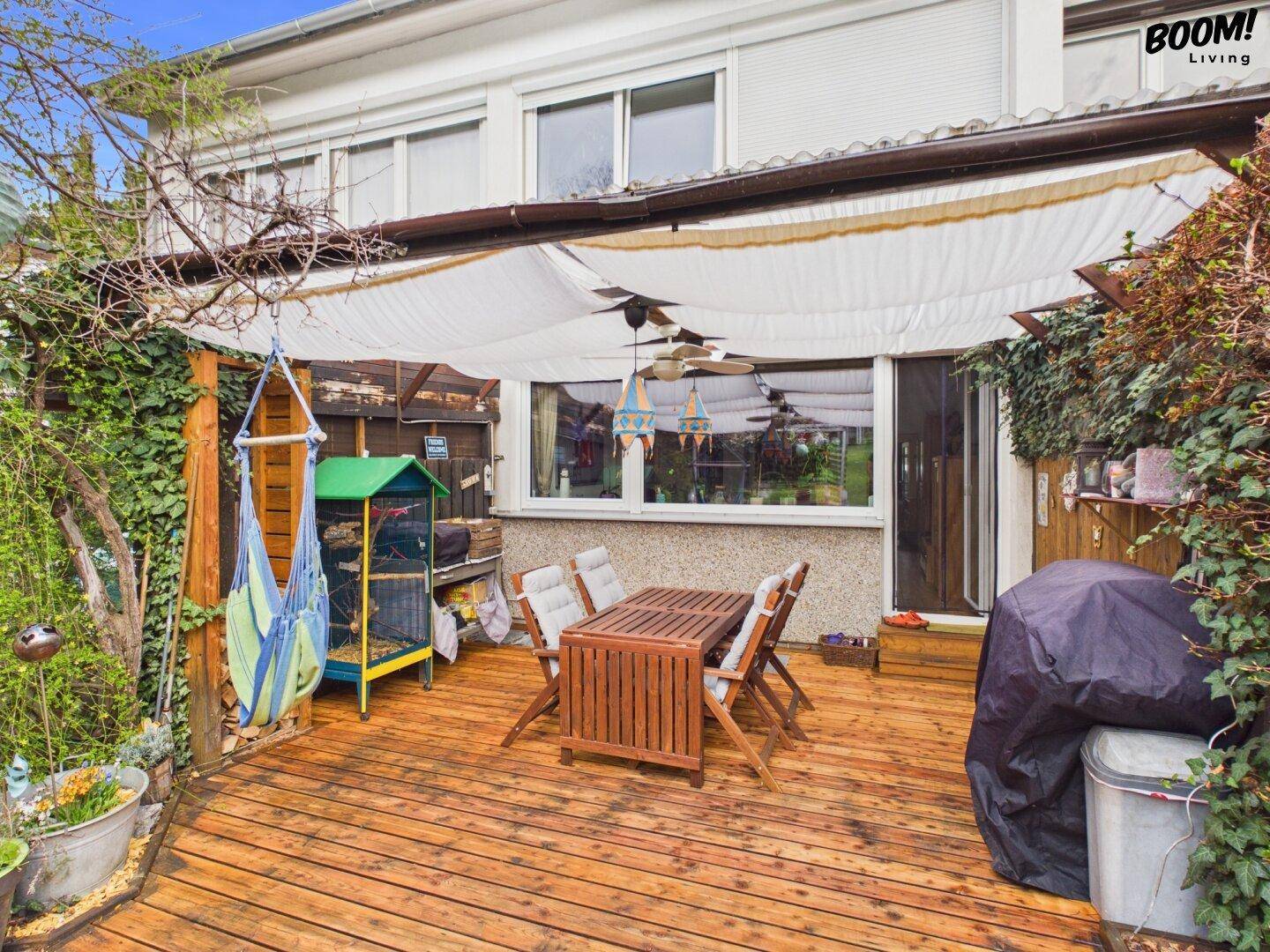 Geräumige Holzterrasse mit Esstisch und Grillbereich, ideal für Mahlzeiten im Freien.
