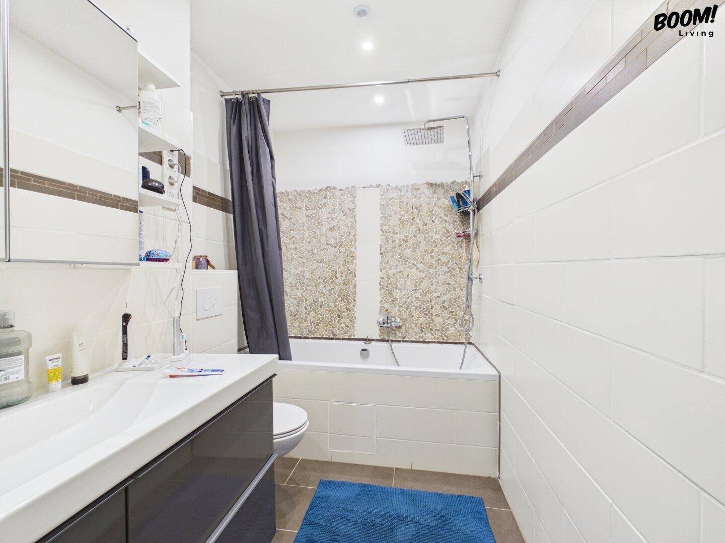 Modernes Badezimmer mit Badewanne, Dusche und weiß gefliesten Wänden.