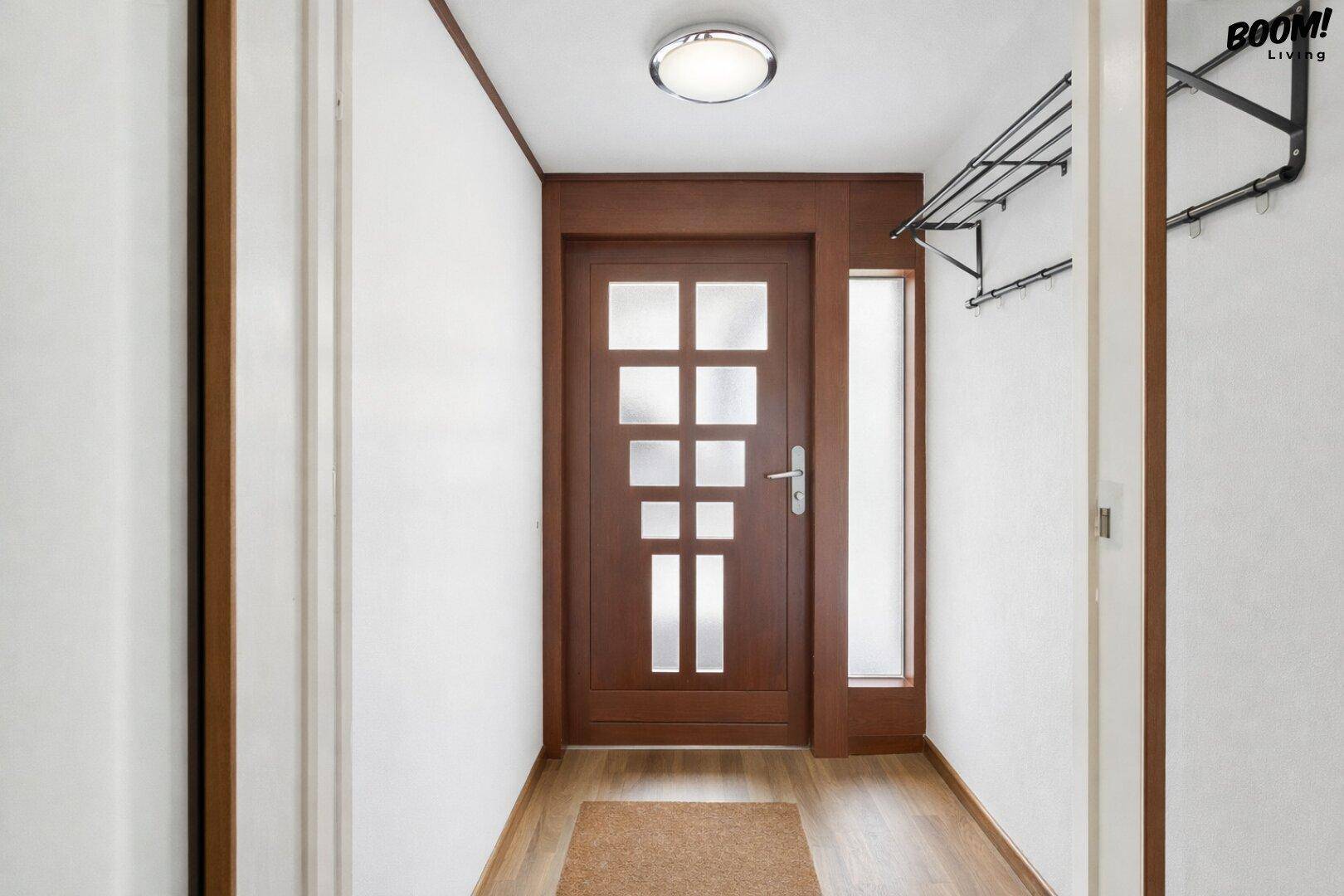 Eingangsbereich mit Holztür, Garderobe und hellem Holzboden.