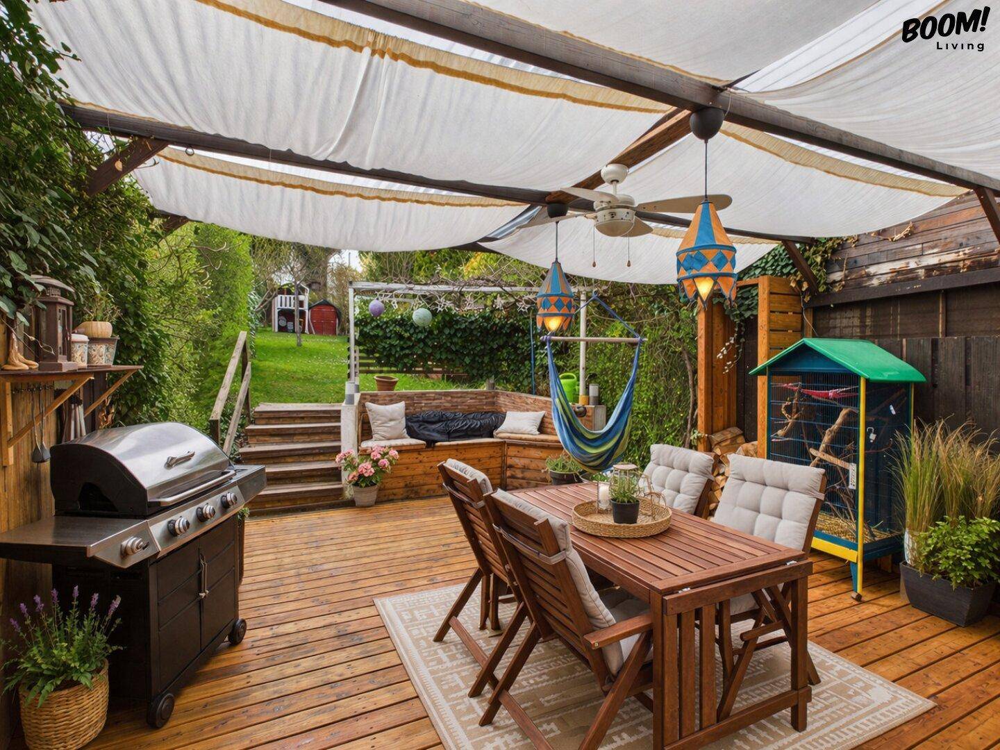 Geräumige Holzterrasse mit Essbereich, Grill und Hängematte, umgeben von viel Grün und einem Gartenblick.