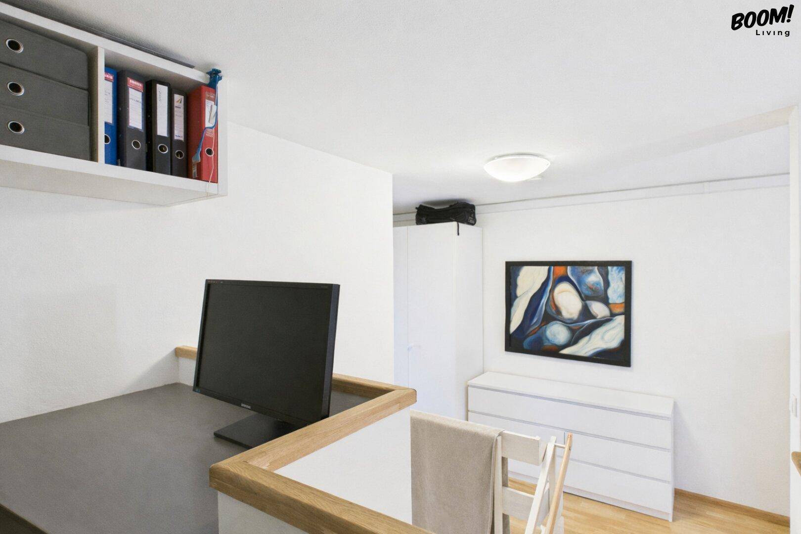 Arbeitsbereich mit Schreibtisch, Monitor und Regalen, ideal für Home-Office.
