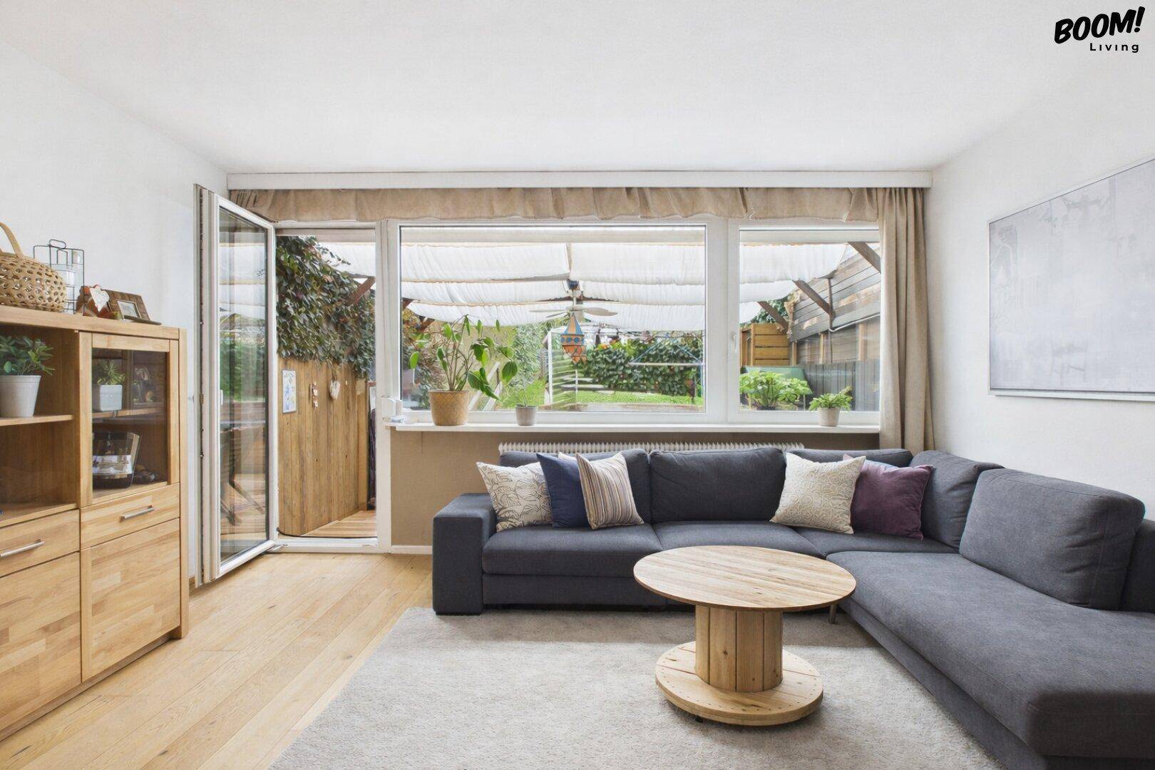 Gemütliches Wohnzimmer mit großem Ecksofa, Holzboden und direktem Gartenzugang.