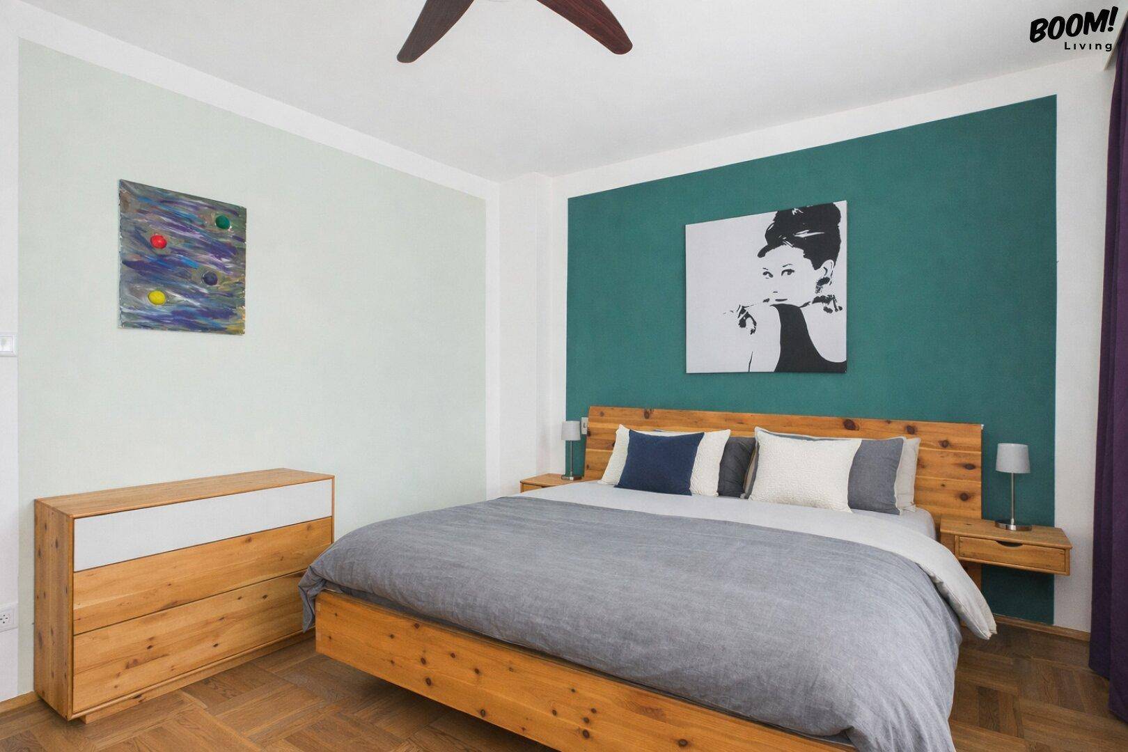 Schlafzimmer mit Holzboden, Doppelbett und grüner Akzentwand, hell und einladend.