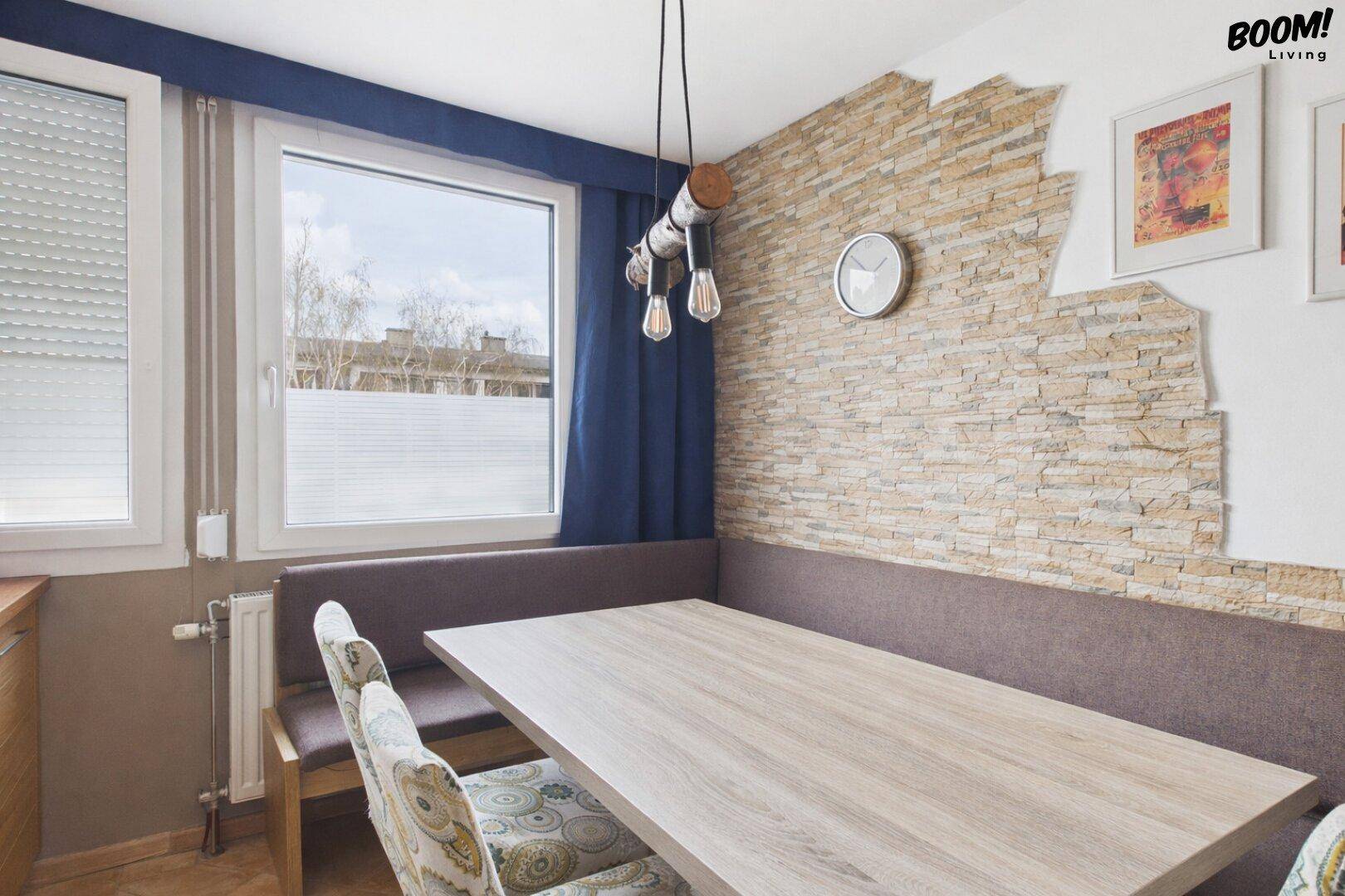 Essbereich mit Holztisch, Sitzbank und dekorativer Steinwand für gemütliche Mahlzeiten.