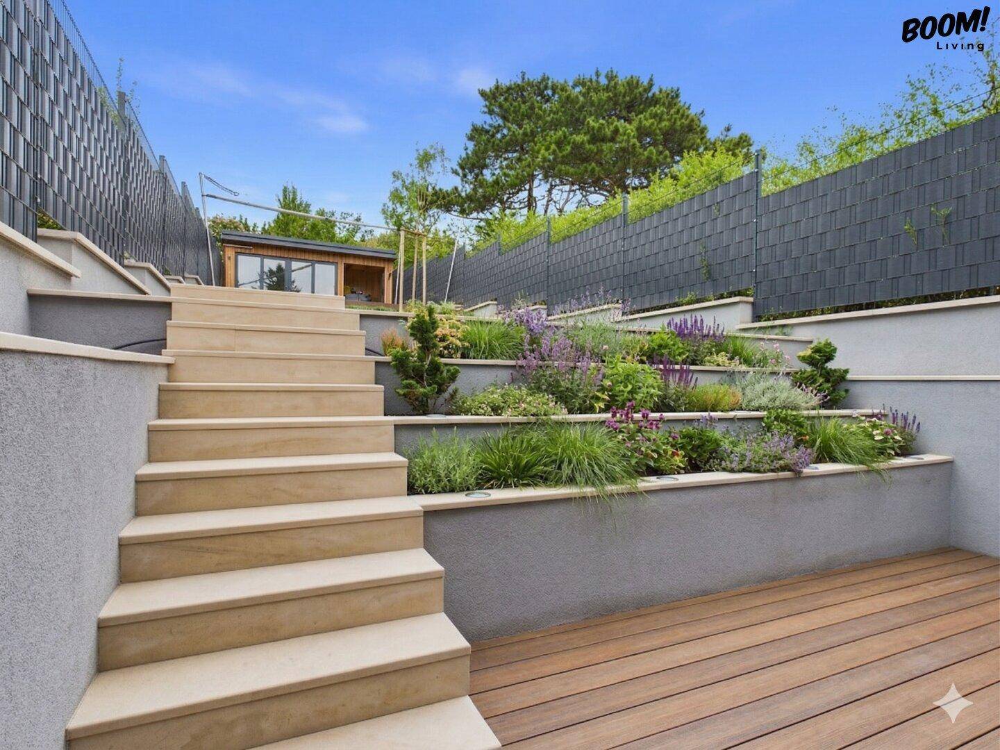 Gestufter Gartenbereich mit Natursteintreppe, vielfältiger Bepflanzung und Holzdeck.