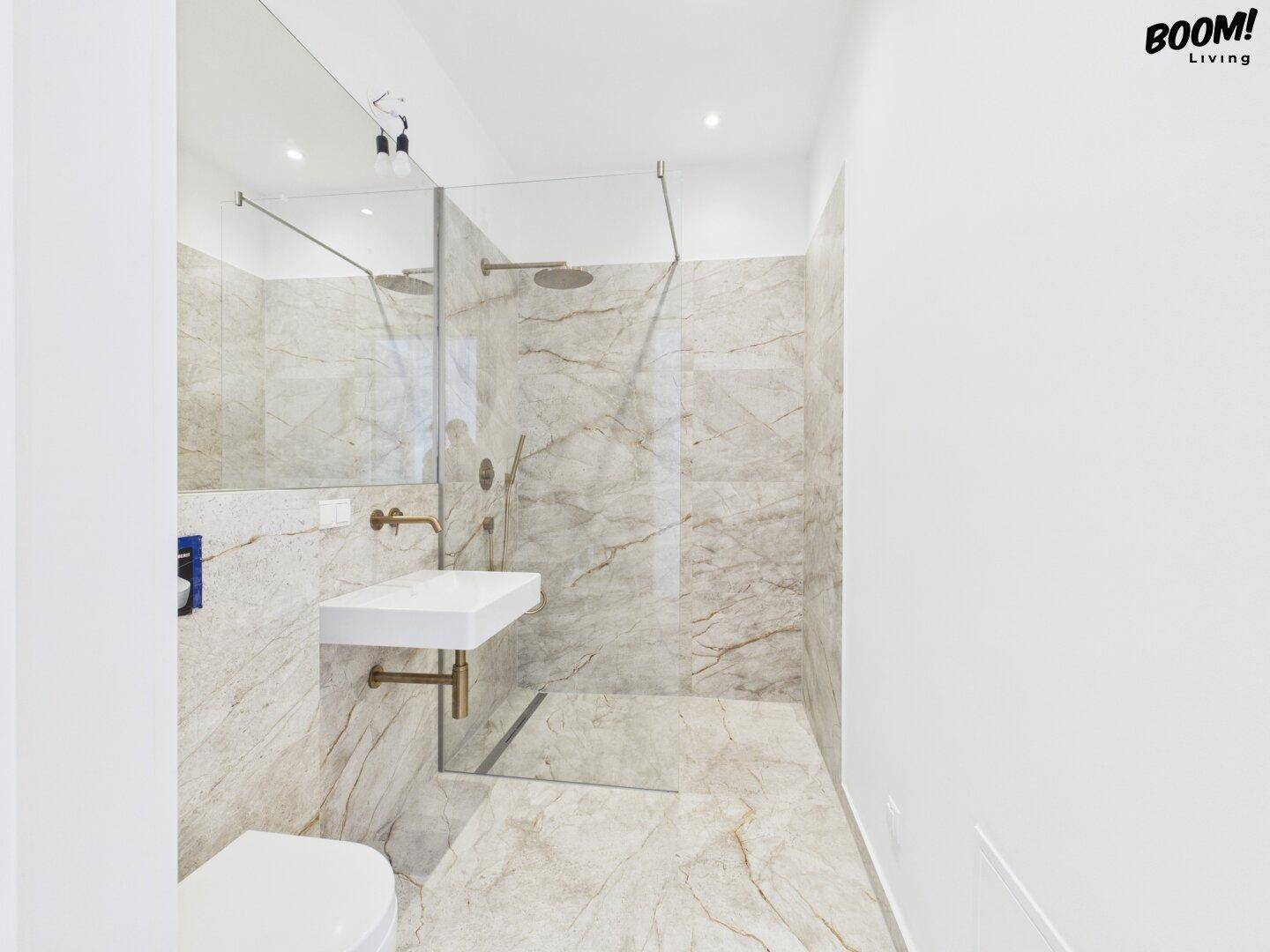 Modernes Badezimmer mit Marmorfliesen, begehbarer Dusche und minimalistischem Waschbecken.