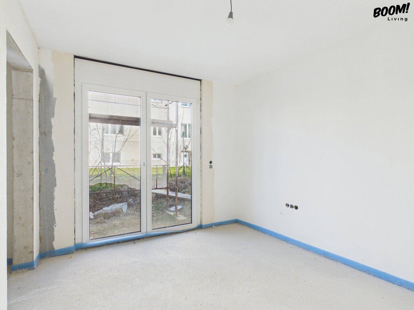 Unfertiger Raum mit Fenster und Rohbauwänden, bereit für den Innenausbau.