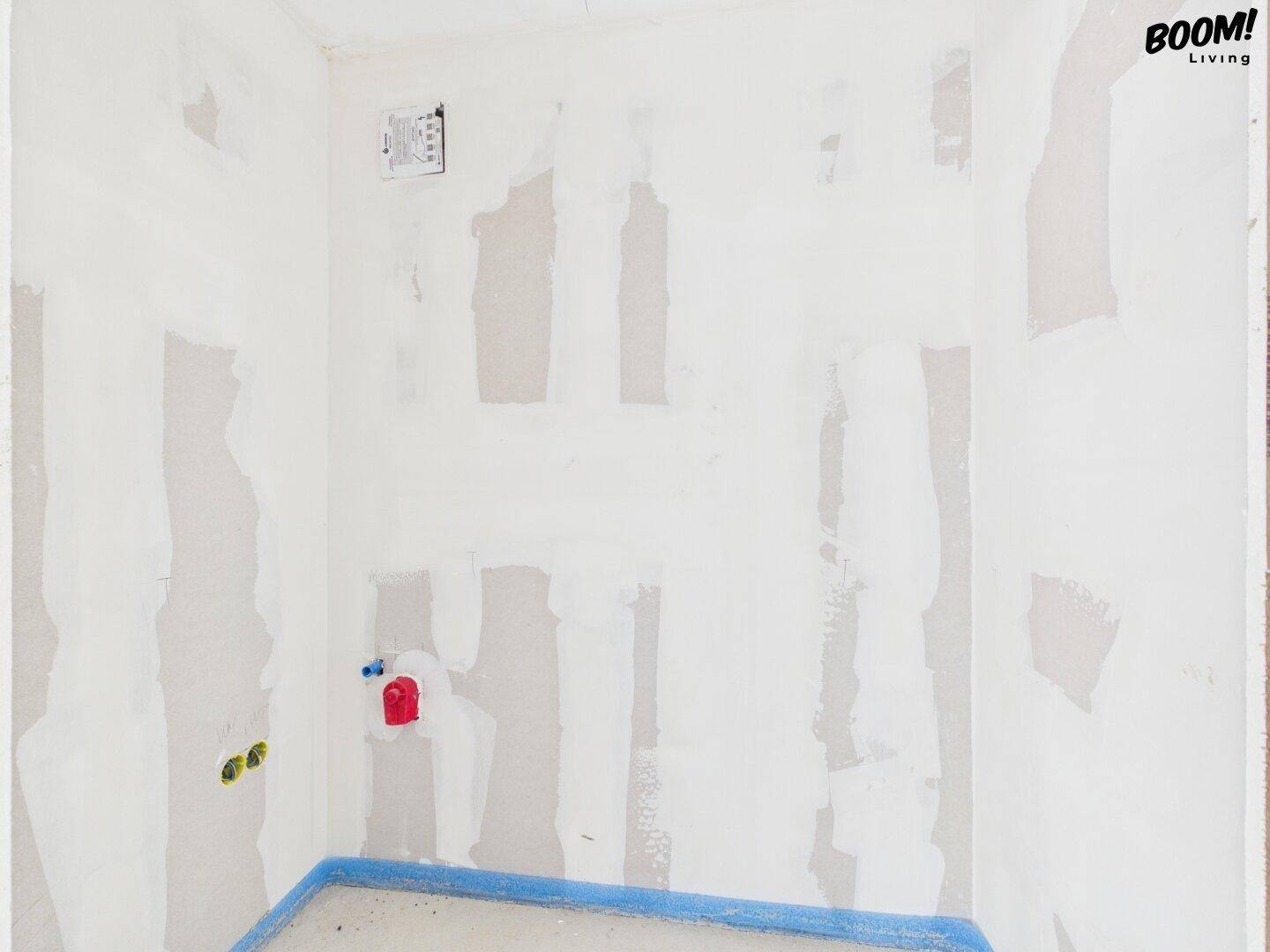 Rohbau-Badezimmerbereich mit vorbereiteten Anschlüssen für eine Dusche.