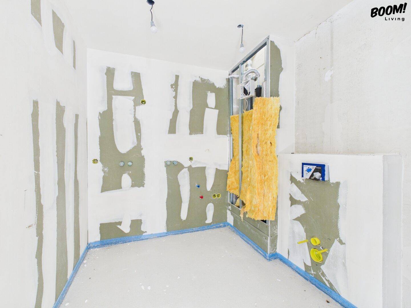 Rohbau eines Badezimmers mit vorbereiteten Installationen für eine Dusche.