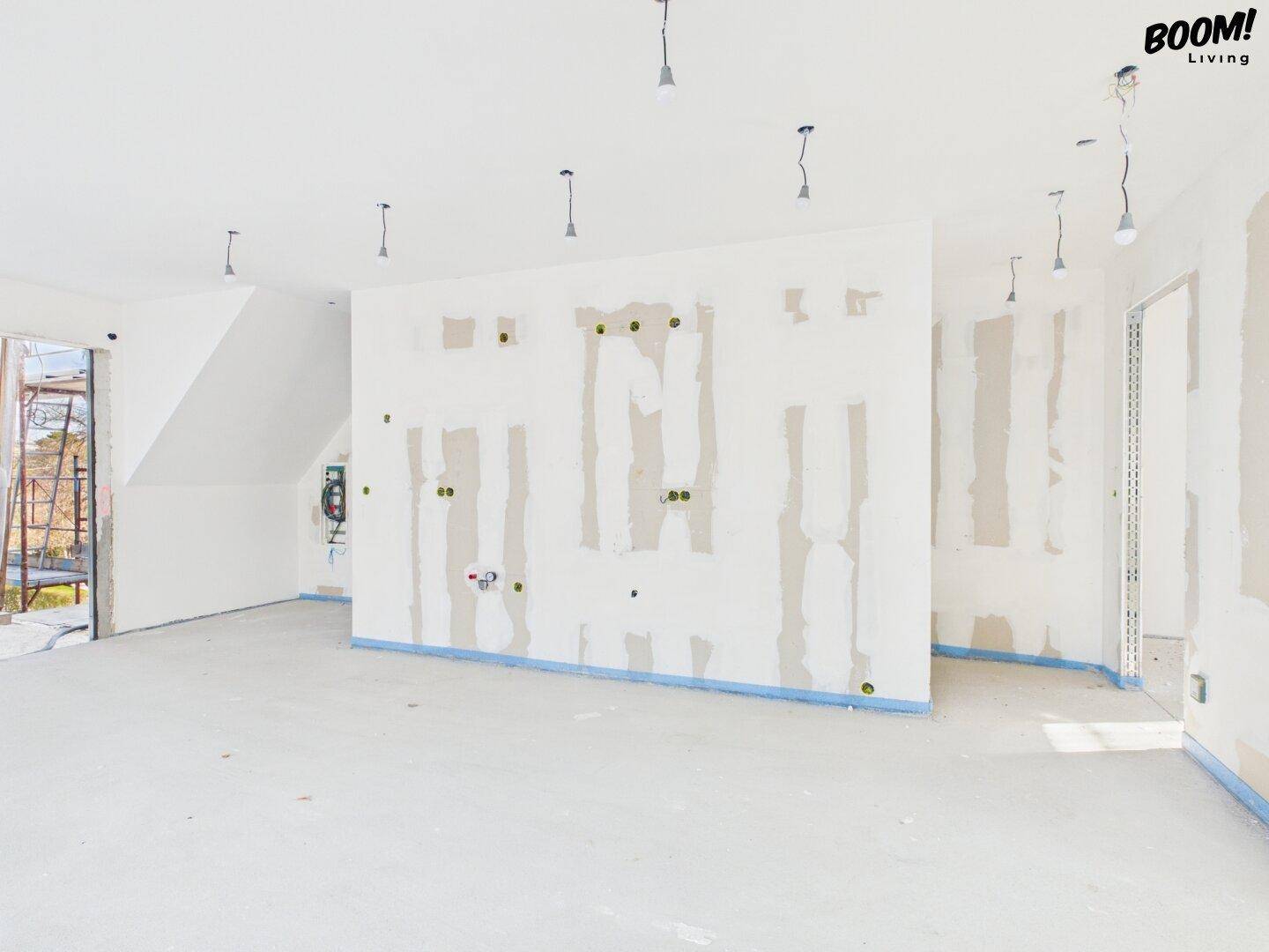 Geräumiger Rohbau-Innenraum mit vorbereiteten Wänden und Decken für den weiteren Ausbau.