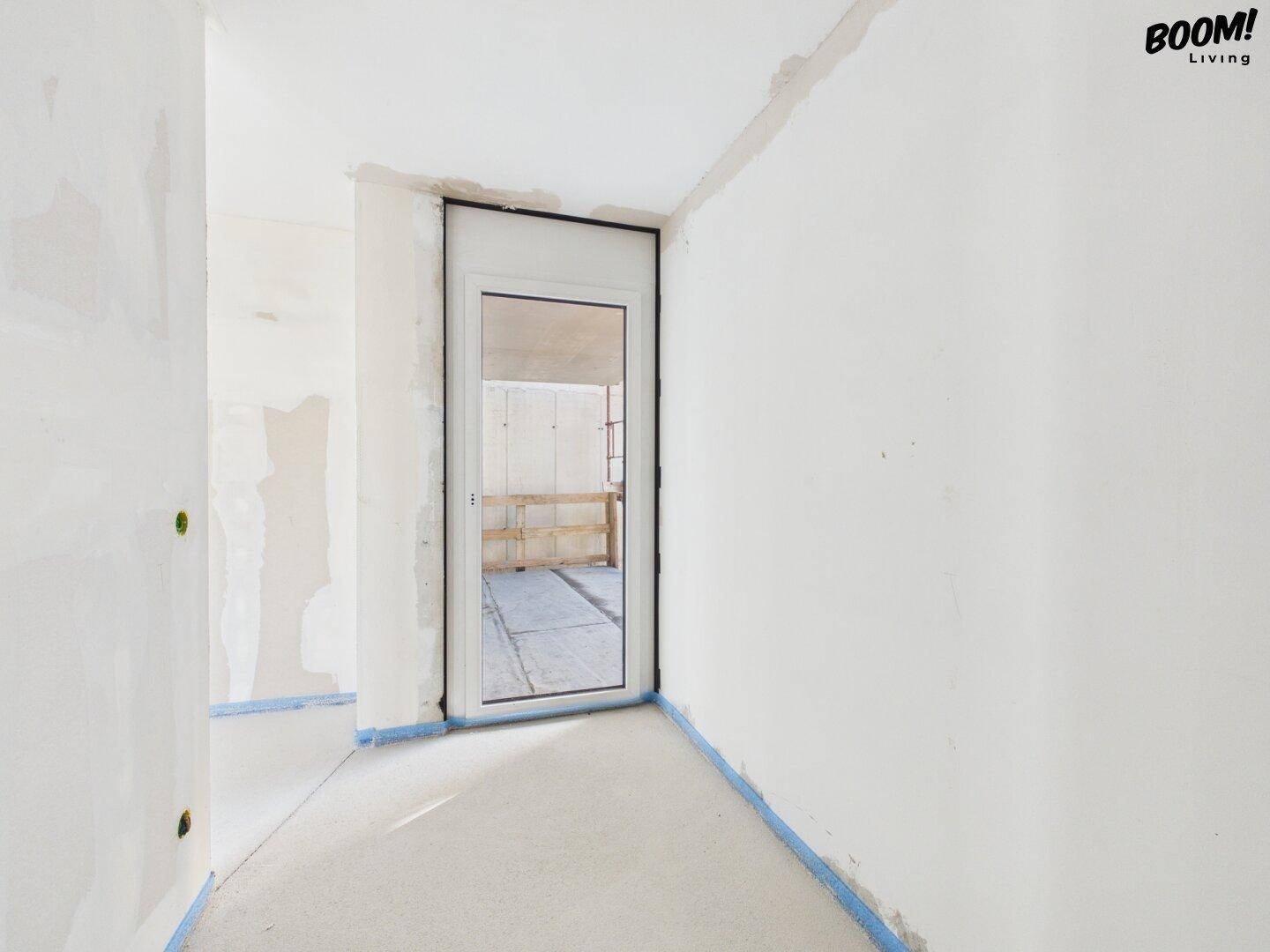 Unfertiger Flurbereich mit einer Tür oder einem schmalen Fenster, bereit für den Ausbau.