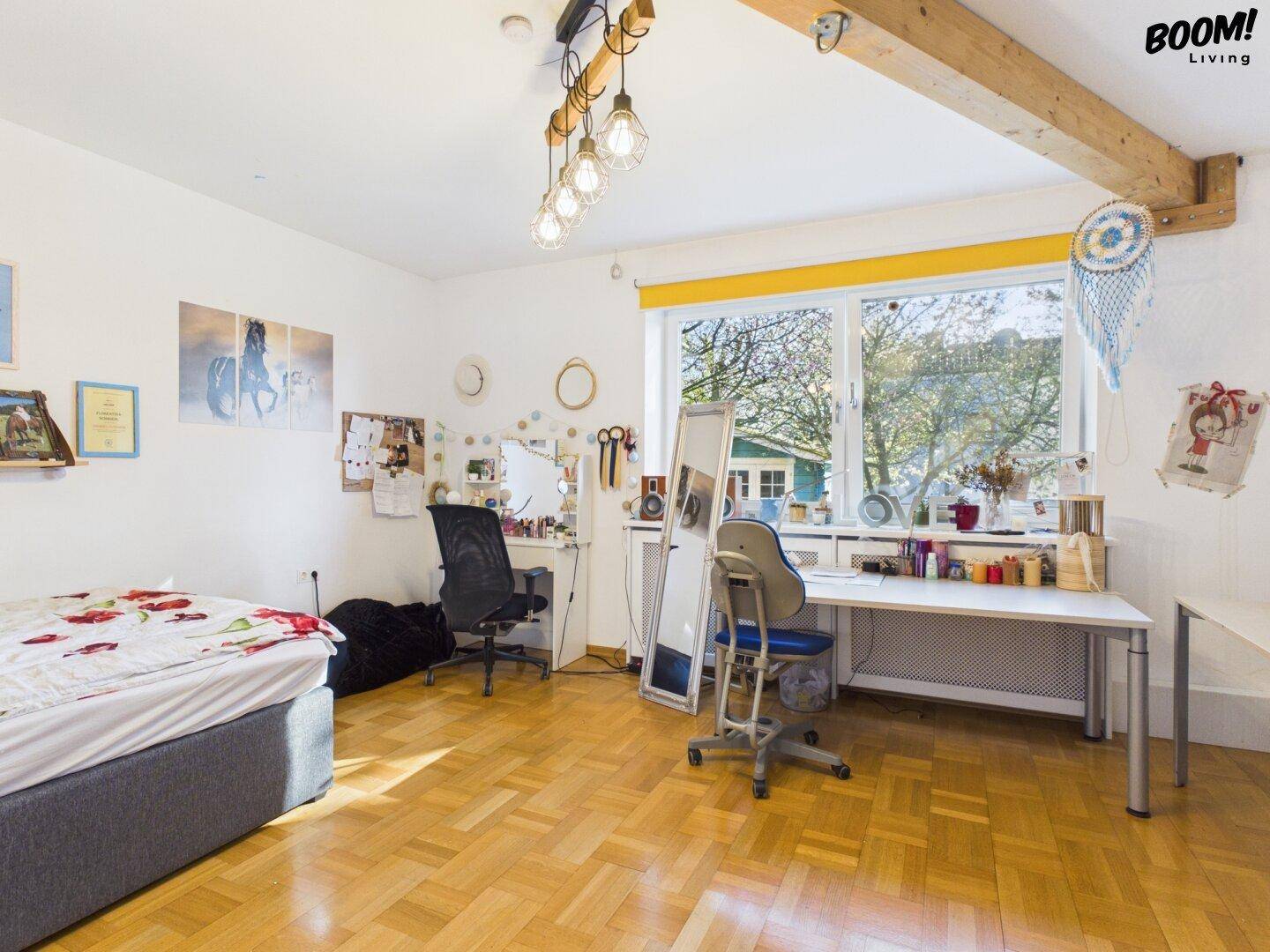 Helles Schlafzimmer mit Holzboden, großem Fenster und sichtbaren Holzbalken an der Decke.