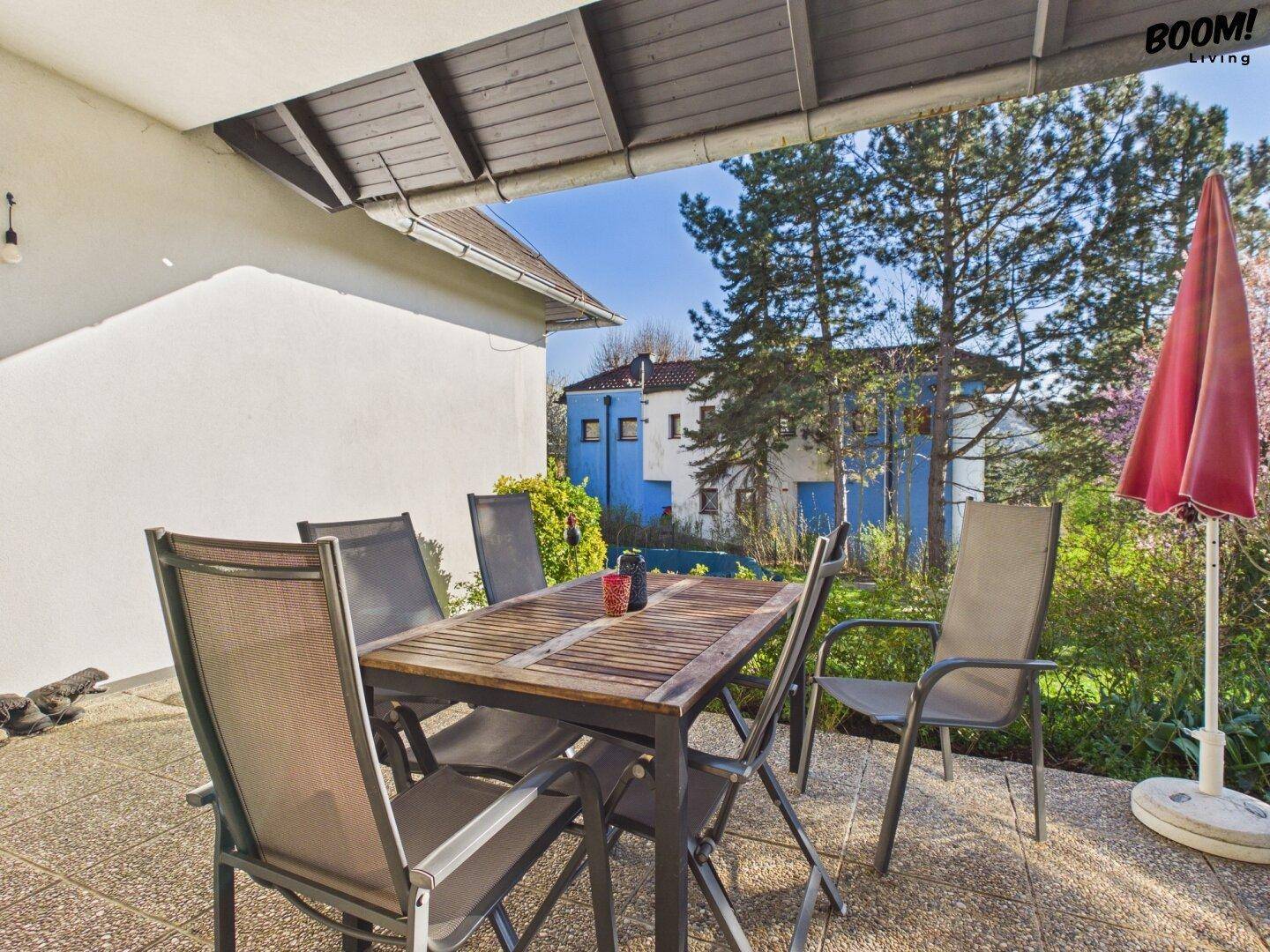 Möblierte Terrasse mit Esstisch und Stühlen, ideal für Mahlzeiten im Freien mit Blick auf das Nachbargebäude.