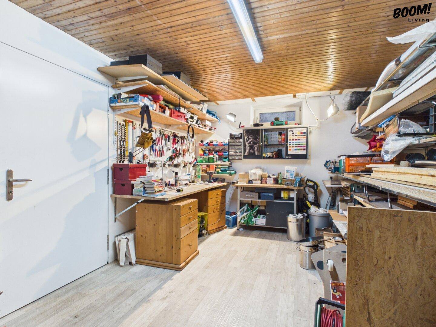Geräumiger Hobbyraum oder Werkstatt mit Holzdecke, vielen Regalen und Arbeitsflächen für Projekte.